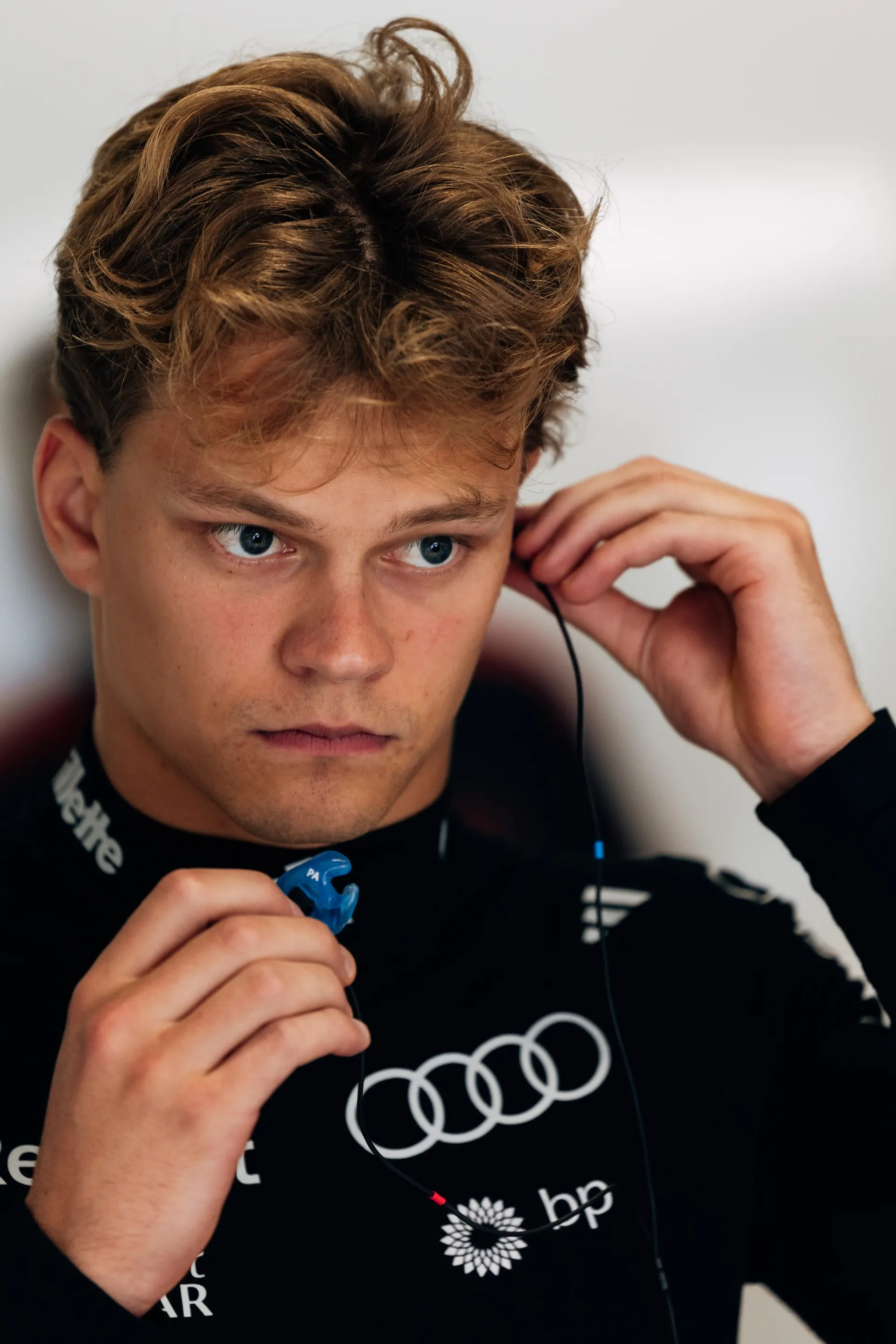 Portrait of Paul Aron driver at the Audi Revolut F1® Team driver during FP1 in Spielberg, adjusting his in-ear communication device while preparing for the opening practice session of the Austrian Grand Prix weekend.