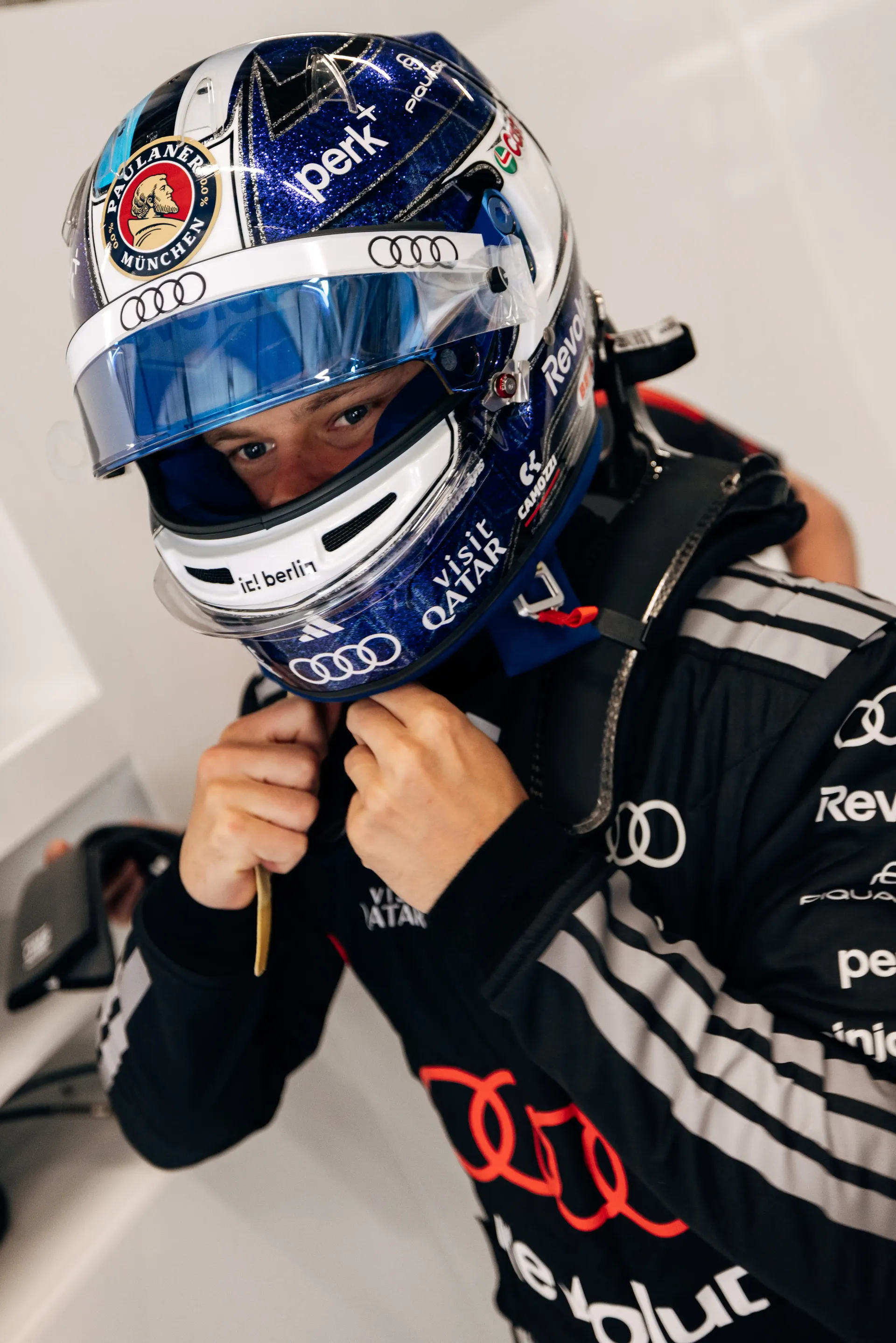 Paul Aron driver at the Audi Revolut F1® Team in full race gear putting on his helmet in the garage during FP1 at the Austrian Grand Prix in Spielberg, preparing for a practice run.