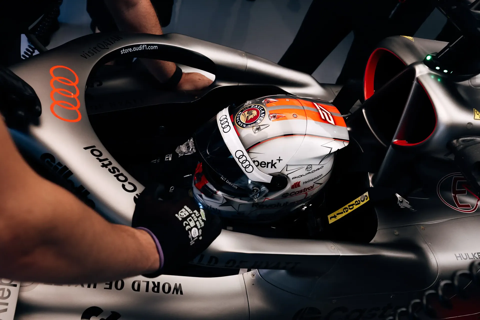 Close-up of Nico Hulkneberg driver at the Audi Revolut F1® Team inside the cockpit area of the Audi R26 during FP1 in Spielberg, with a helmet placed inside the cockpit as the team prepares for practice running.