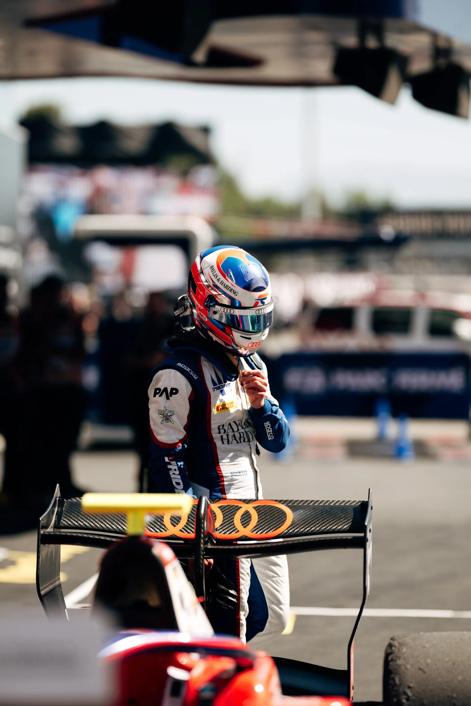 Freddie Slater standing beside his F3 car on the grid, adjusting his helmet strap ahead of the sprint race start.