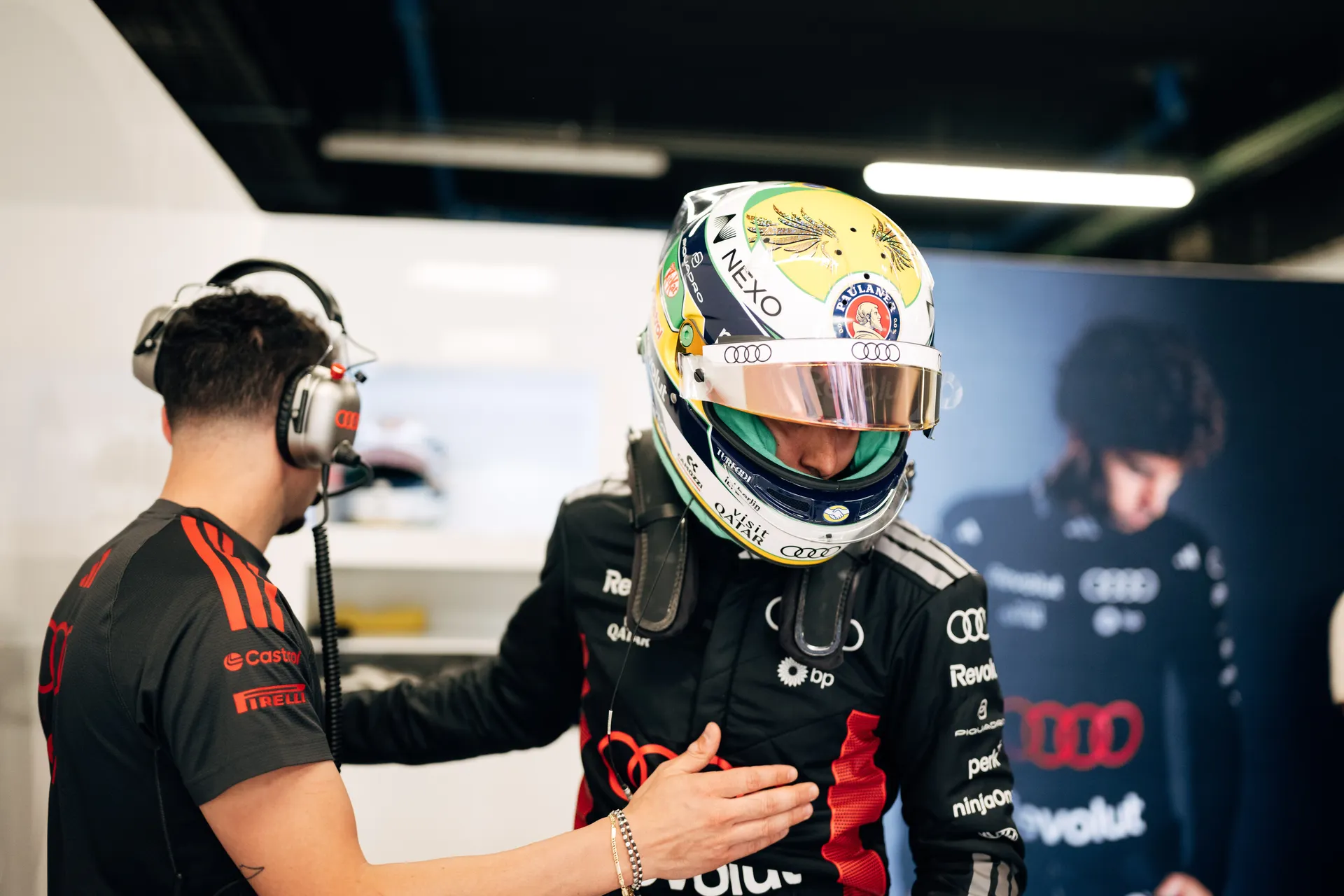 Gabriel Bortoleto wearing a helmet with Brazilian colors stands in the garage while a team member gives final instructions before the run