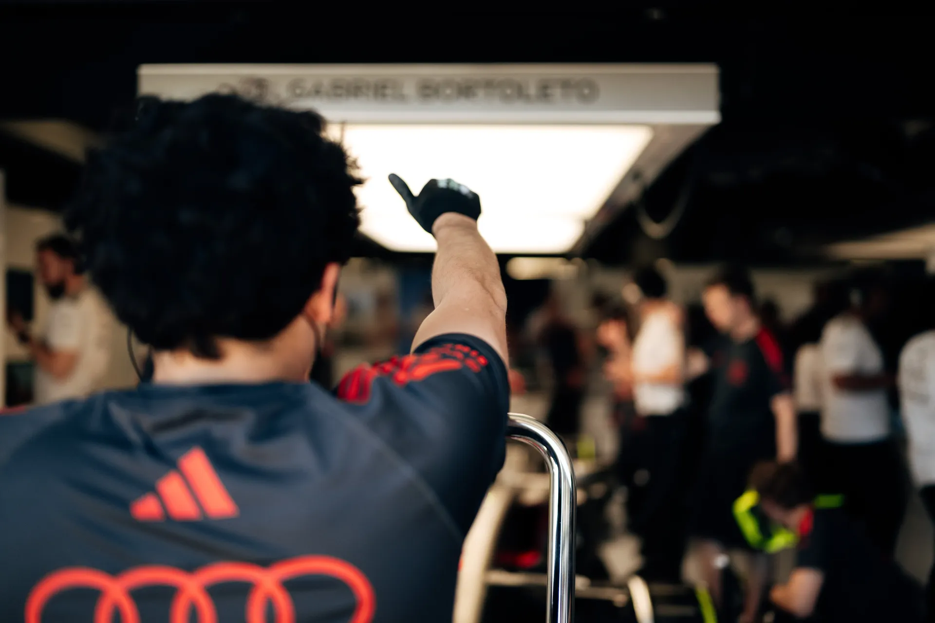 Audi Revolut F1® Team crew member signals inside the garage while pointing toward the pit lane, coordinating car release