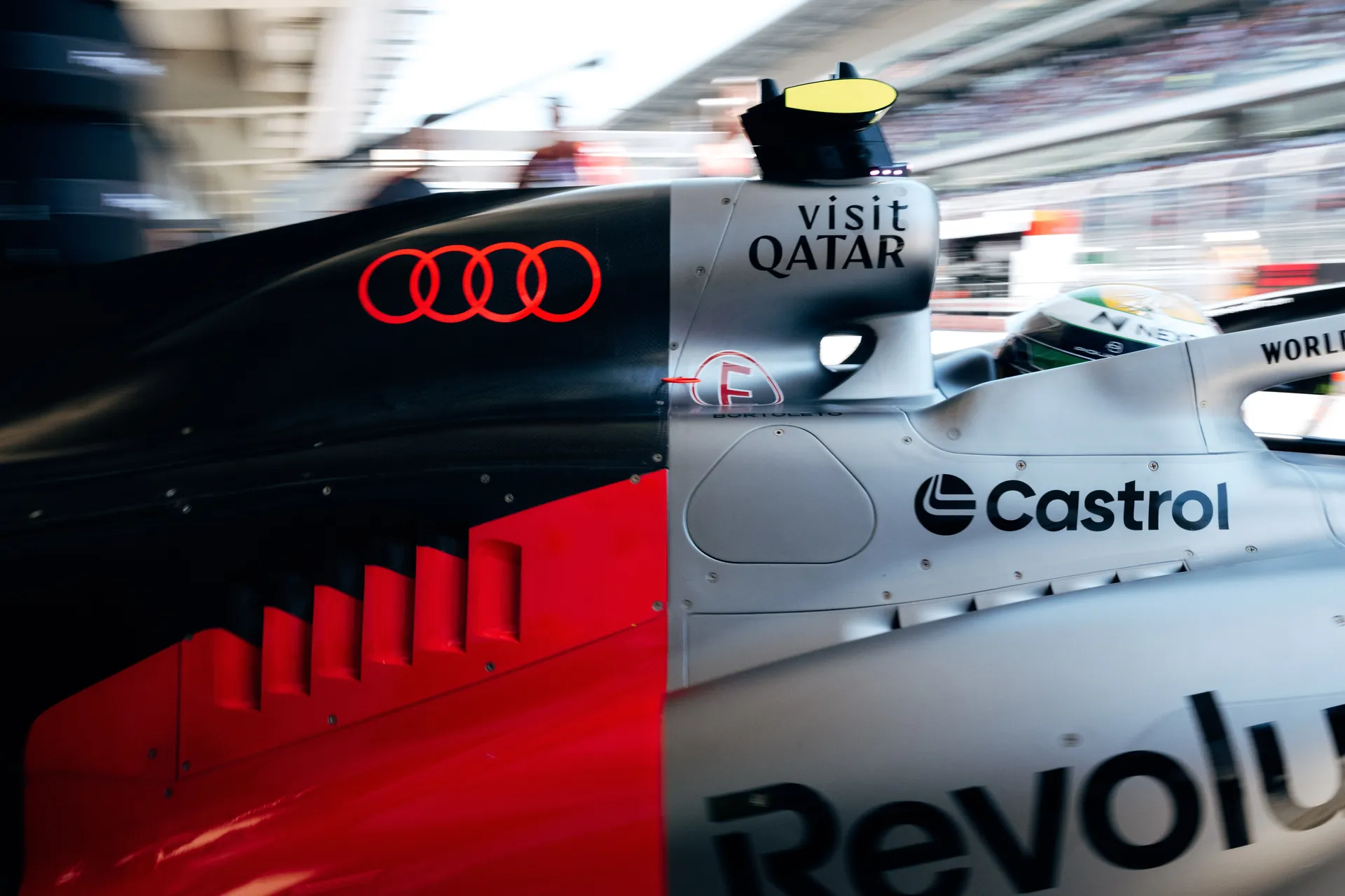Dynamic close up of the Audi Revolut F1® Team car bodywork with illuminated Audi rings and sponsor logos during pit lane movement