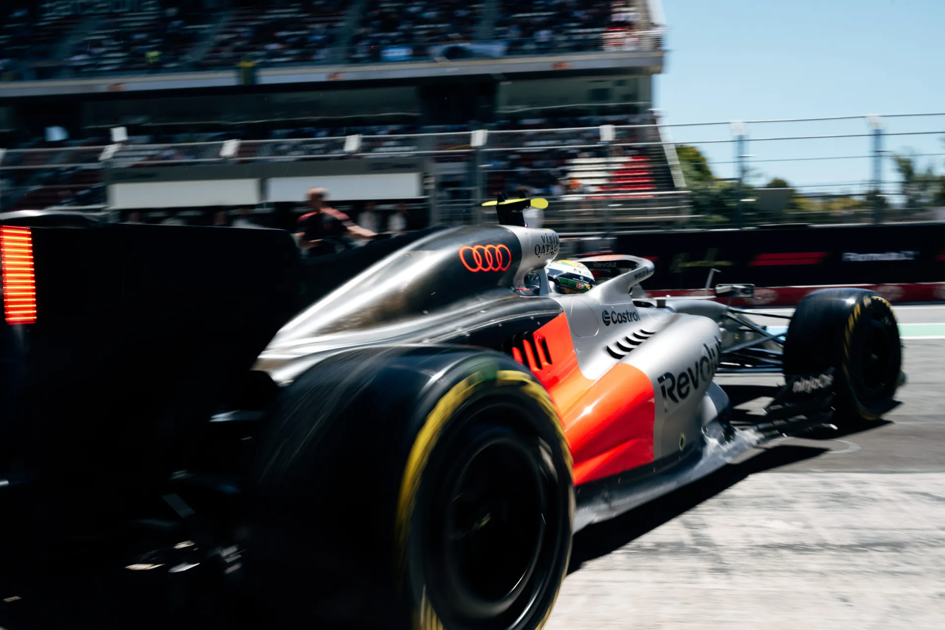 Rear three quarter view of car number 5 accelerating out of the pit lane with motion blur and grandstands in the background