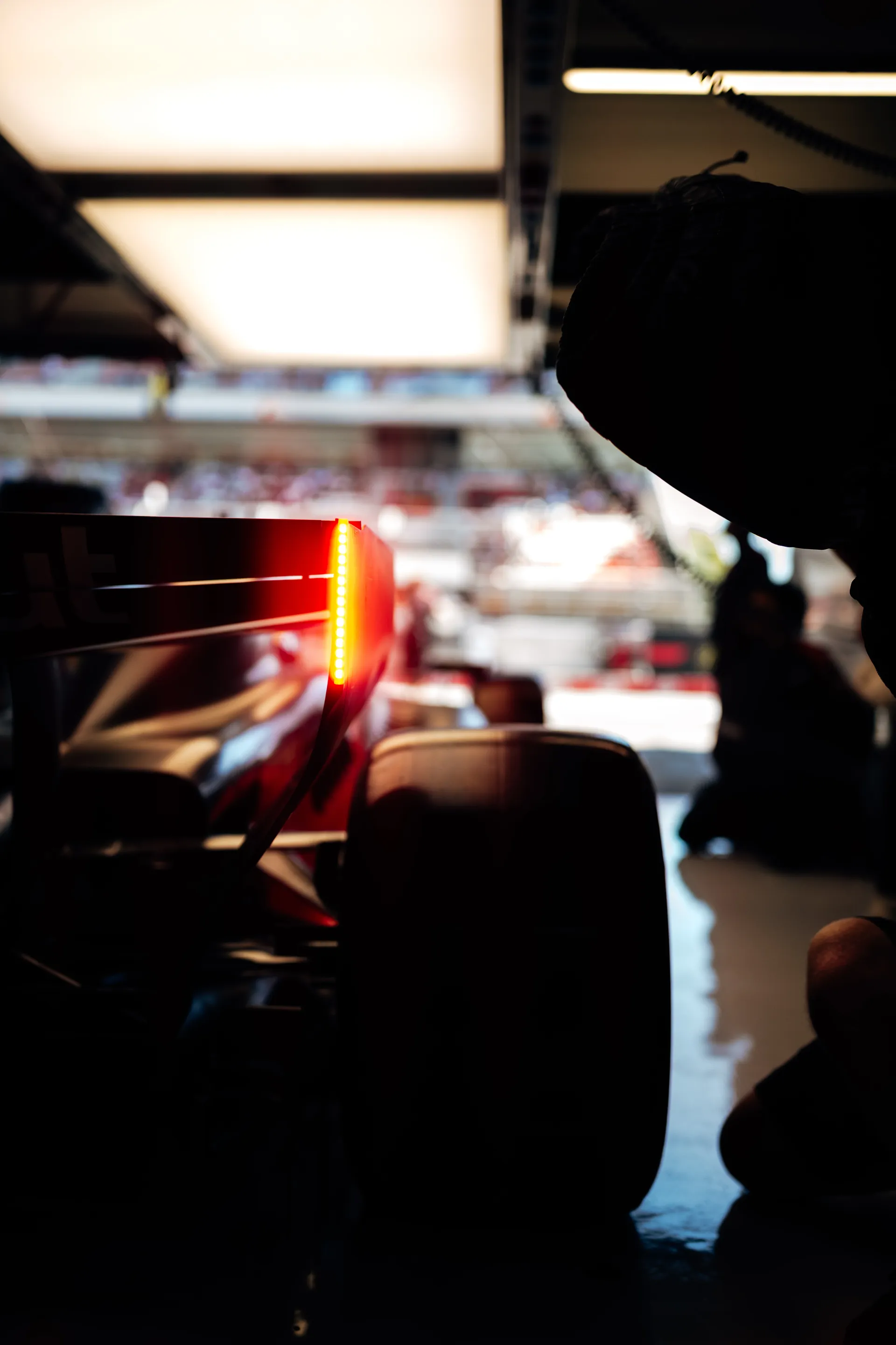 Close-up of the rear wing and rain light of an Audi Revolut F1® Team car inside the garage, with a crew member crouched nearby.