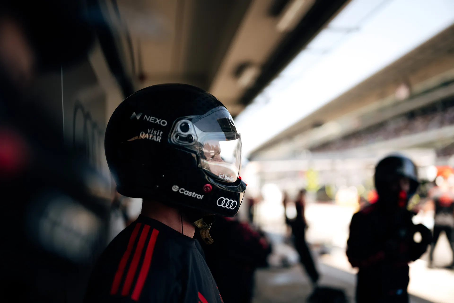 Close-up of an Audi Revolut F1® Team mechanic wearing a helmet, looking toward pit lane during session activity.