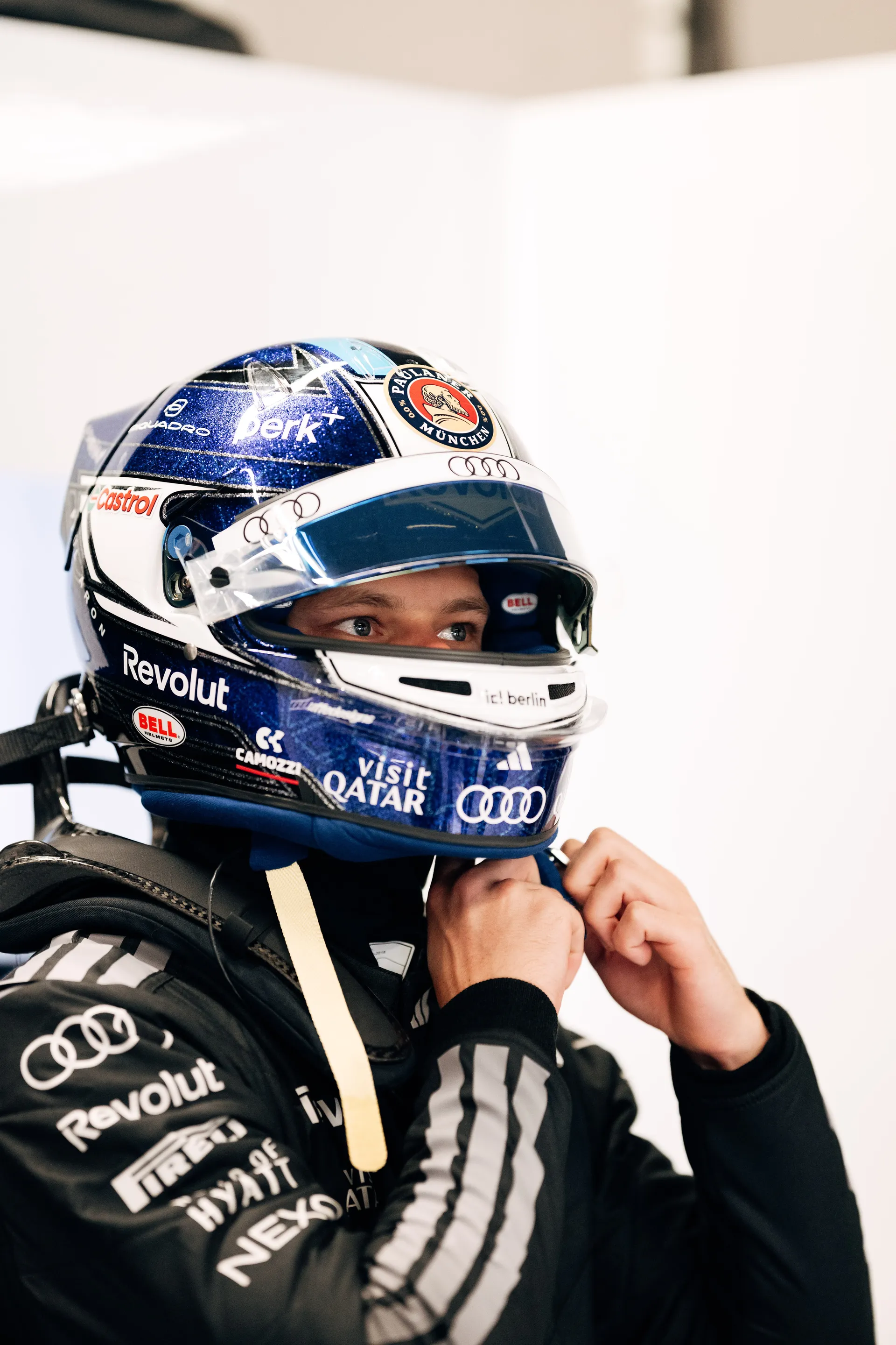 Paul Aron fastening his helmet inside the Audi Revolut F1® Team garage, focused before a session.