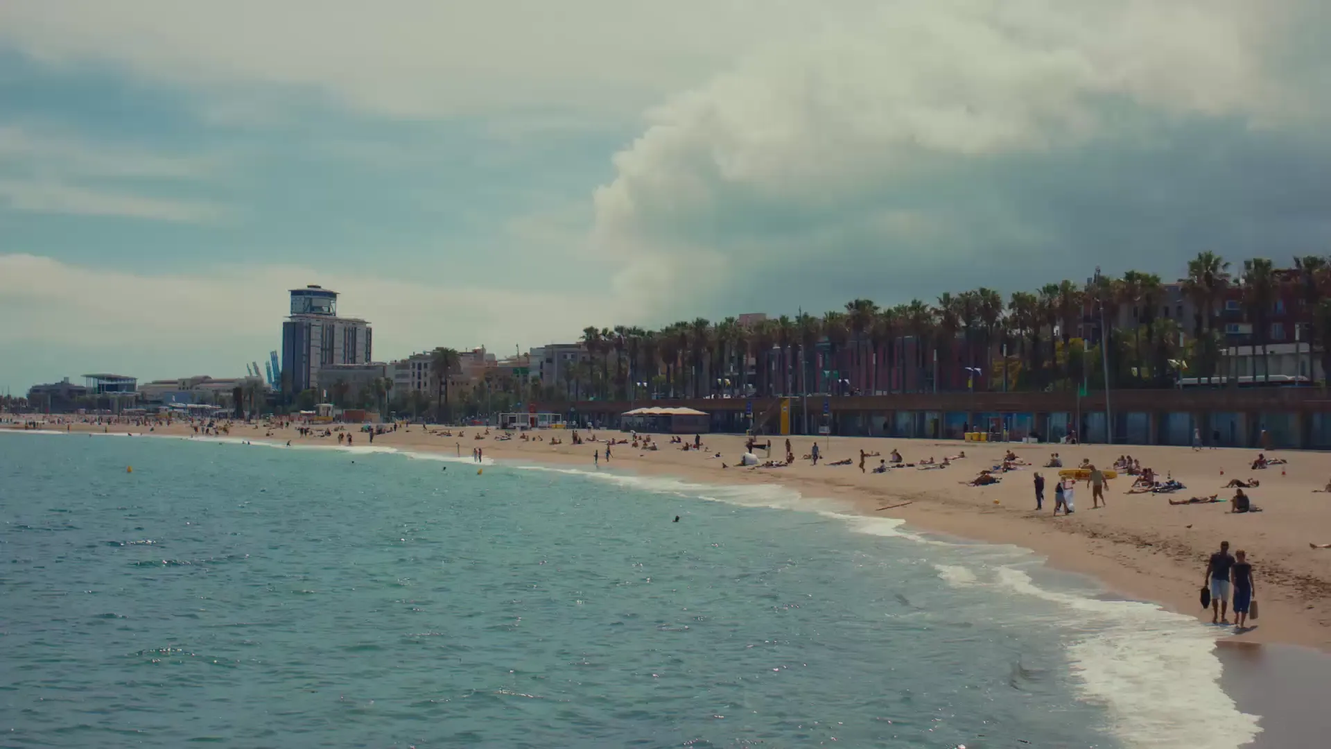 Barcelona beach scene with people relaxing by the sea under clear sky