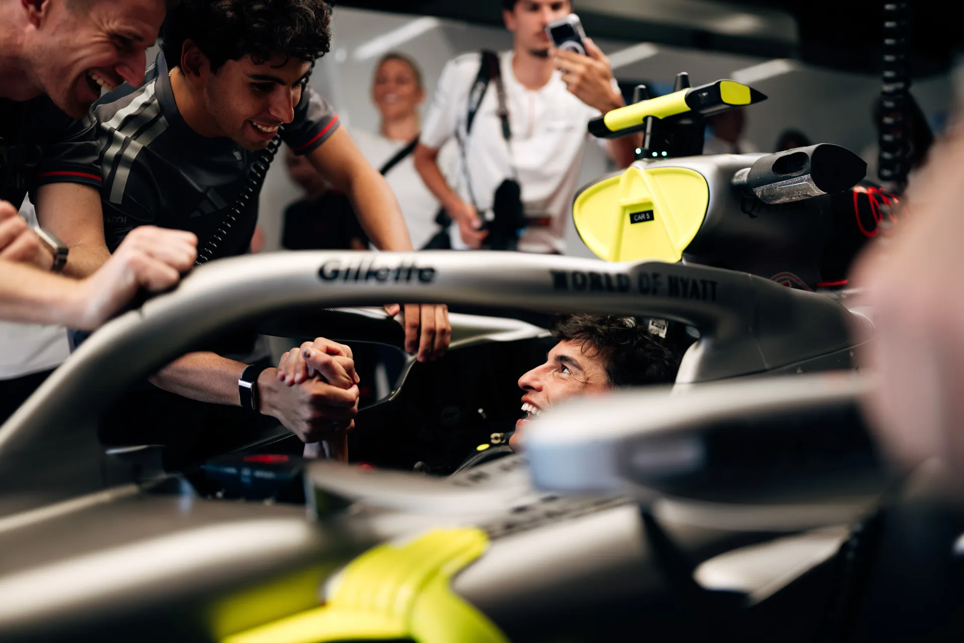 Who is sitting inside the Audi Revolut F1® Team car in the garage, interacting with a team member while others observe