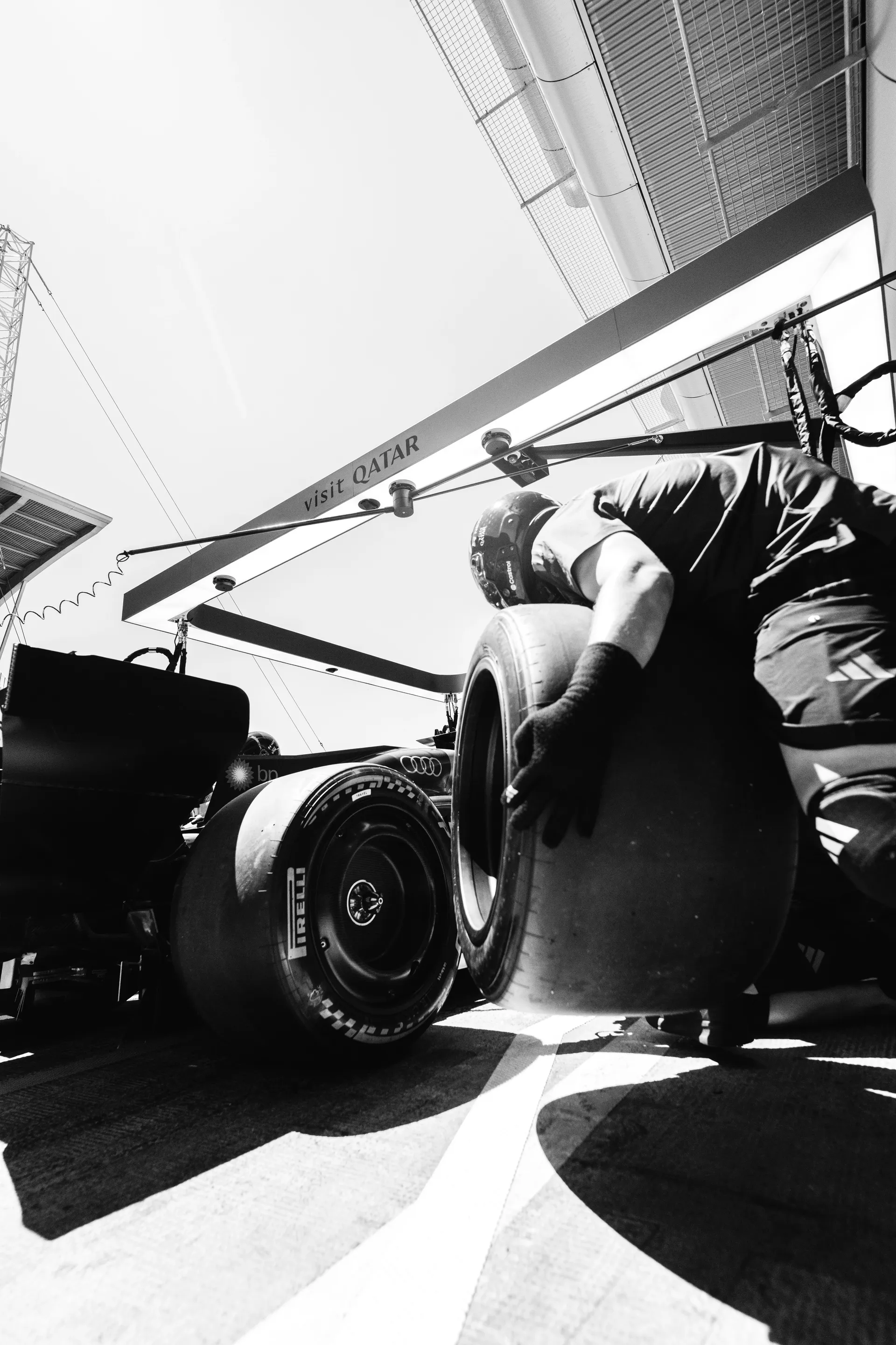 Close-up black and white shot of a pit crew member handling Pirelli tires during a pit stop sequence
