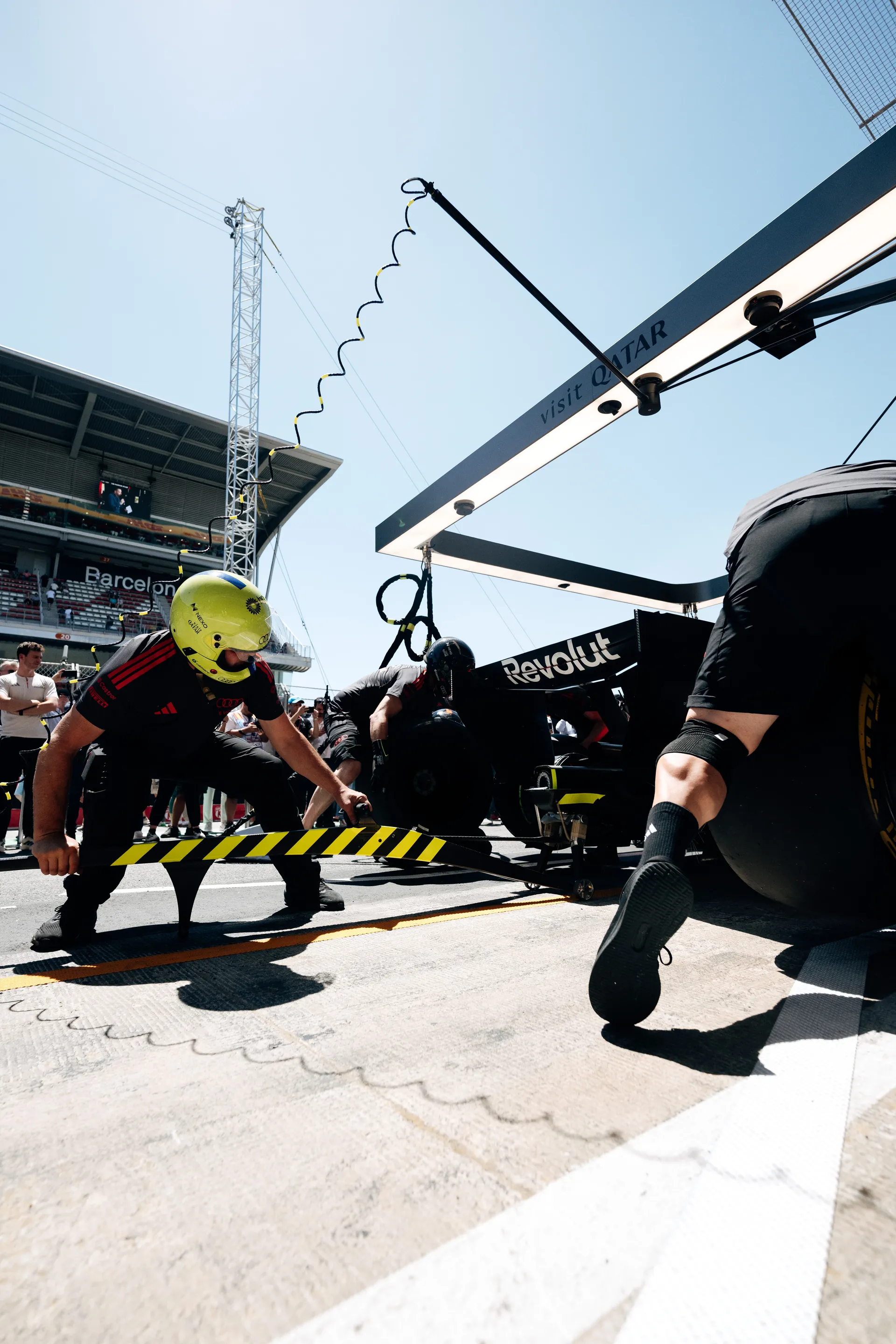 Low-angle view of Audi Revolut F1® Team pit crew executing a tire change during a high-speed pit stop in Barcelona