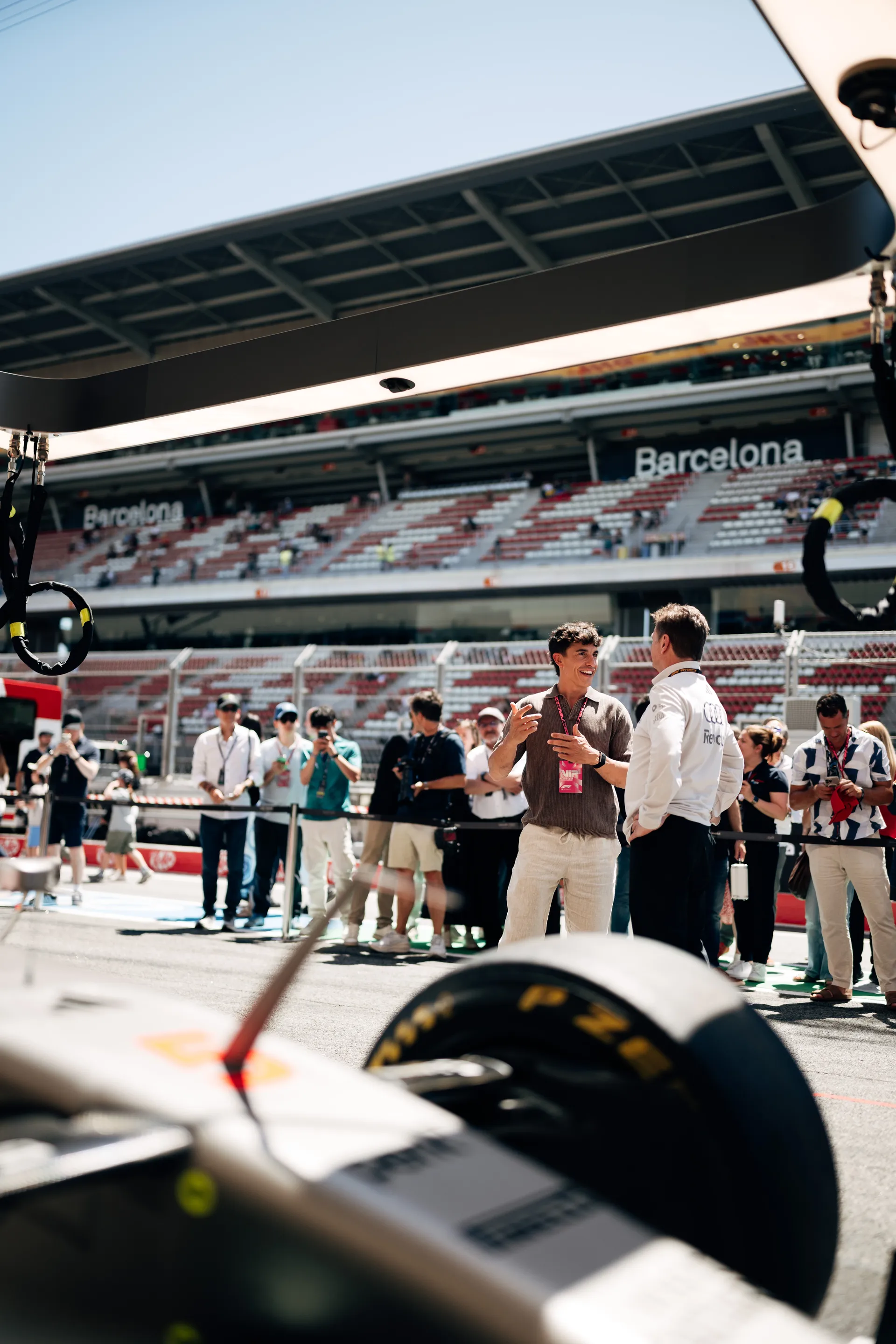 Marc Márquez talking Allan McNish from Audi Revolut F1® Team representative on the pit lane at Circuit de Barcelona Catalunya with grandstand in background