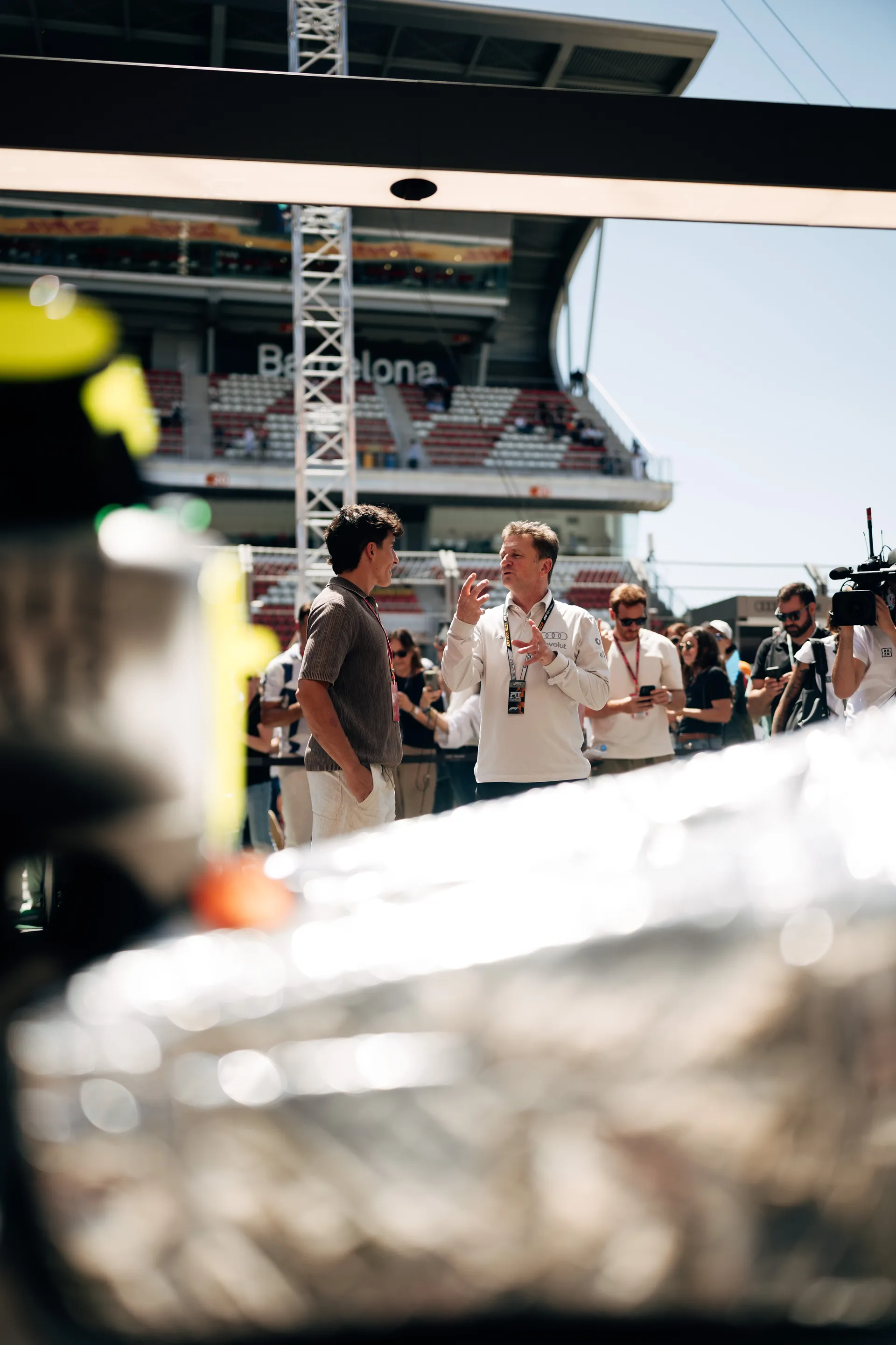 Marc Márquez in conversation with Allan McNish from Audi Revolut F1® Team near the garage during Barcelona race weekend with media behind
