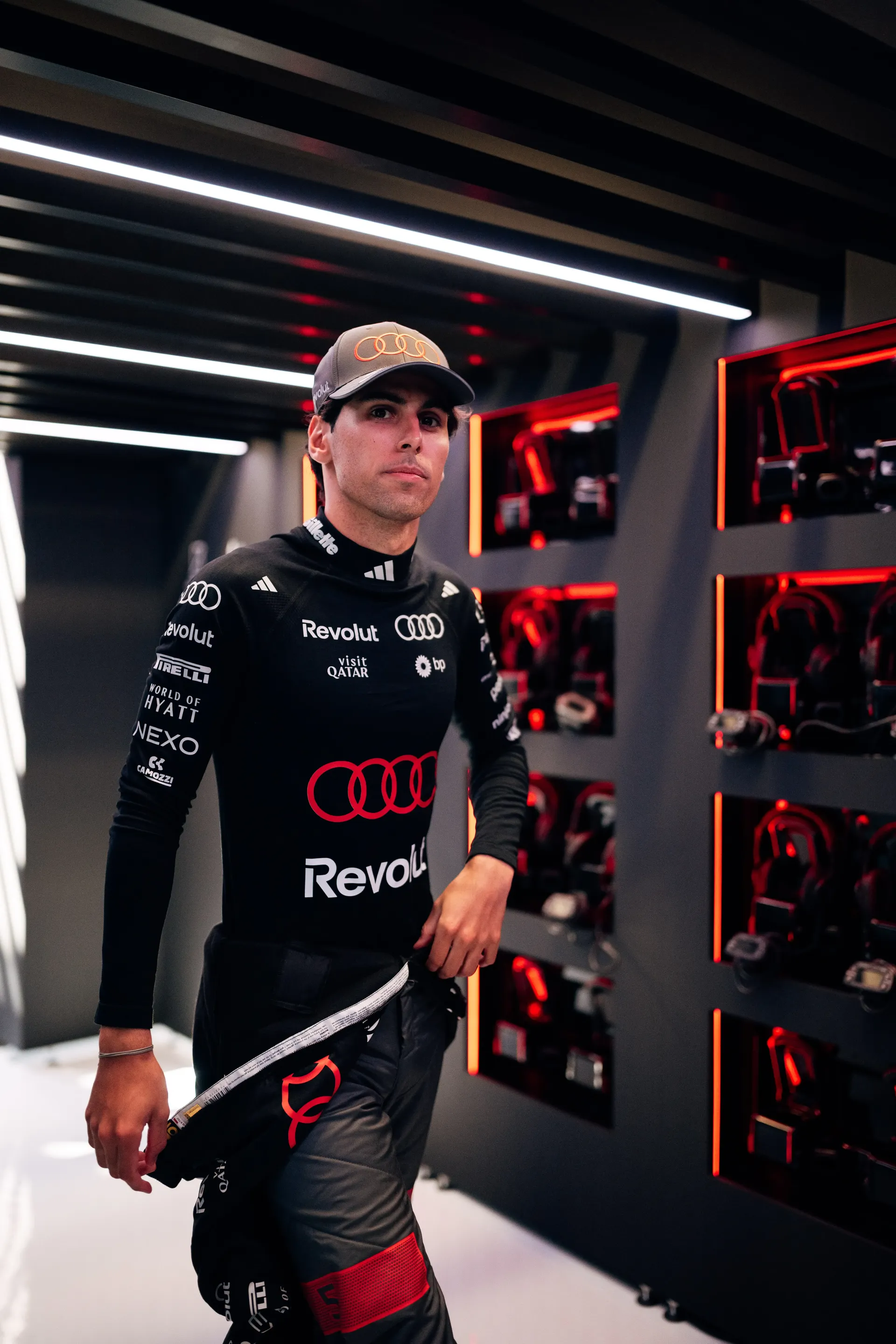 Gabriel Bortoleto walking through the Audi Revolut F1® Team garage area in full race suit
