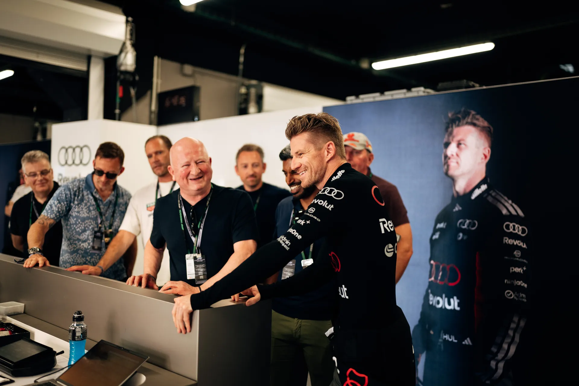 Nico Hulkenberg engaging with guests and team members inside the Audi Revolut F1® Team garage next to a driver display