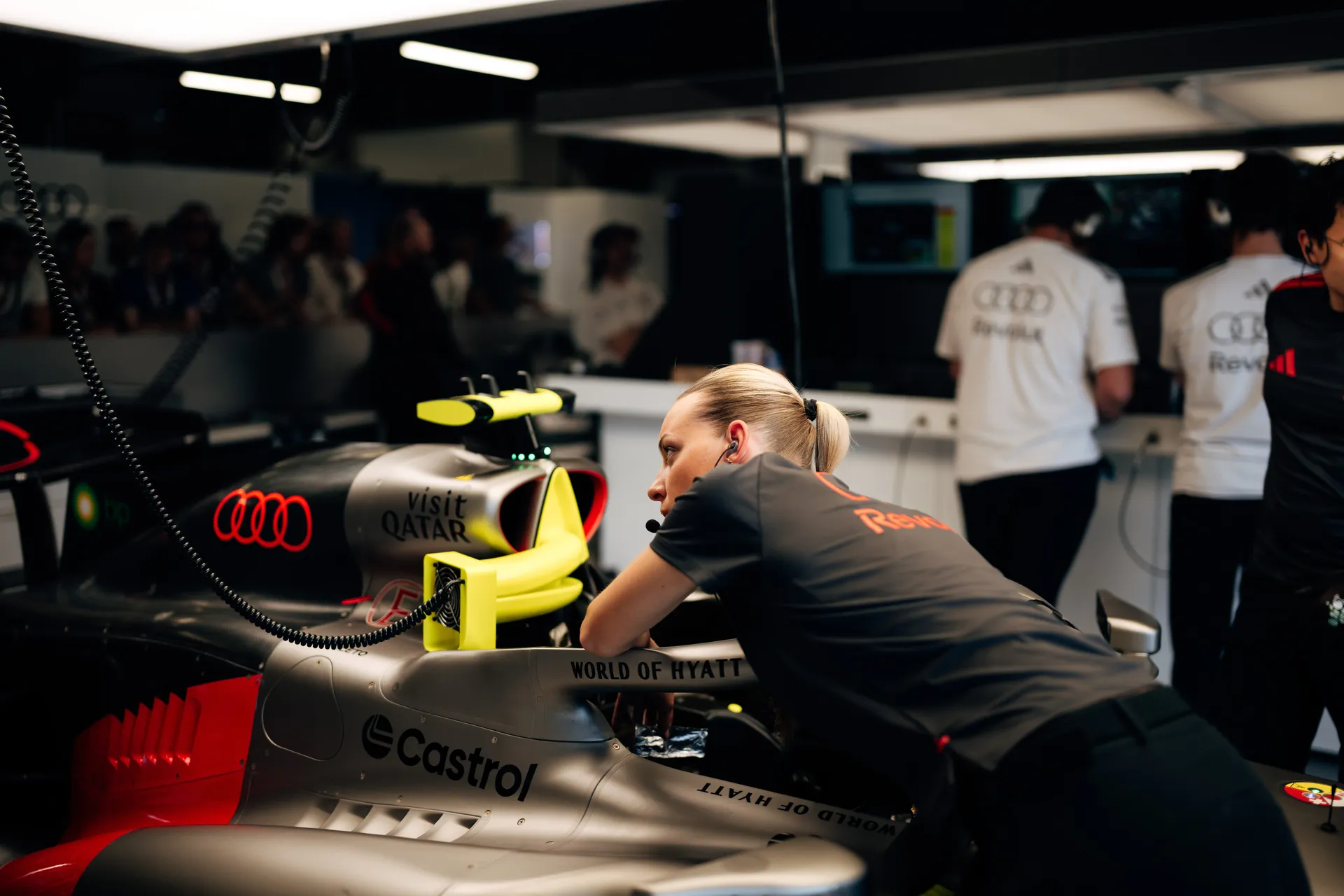 Audi Revolut F1® Team race engineer leaning over the car in the garage, monitoring setup and communicating with the crew