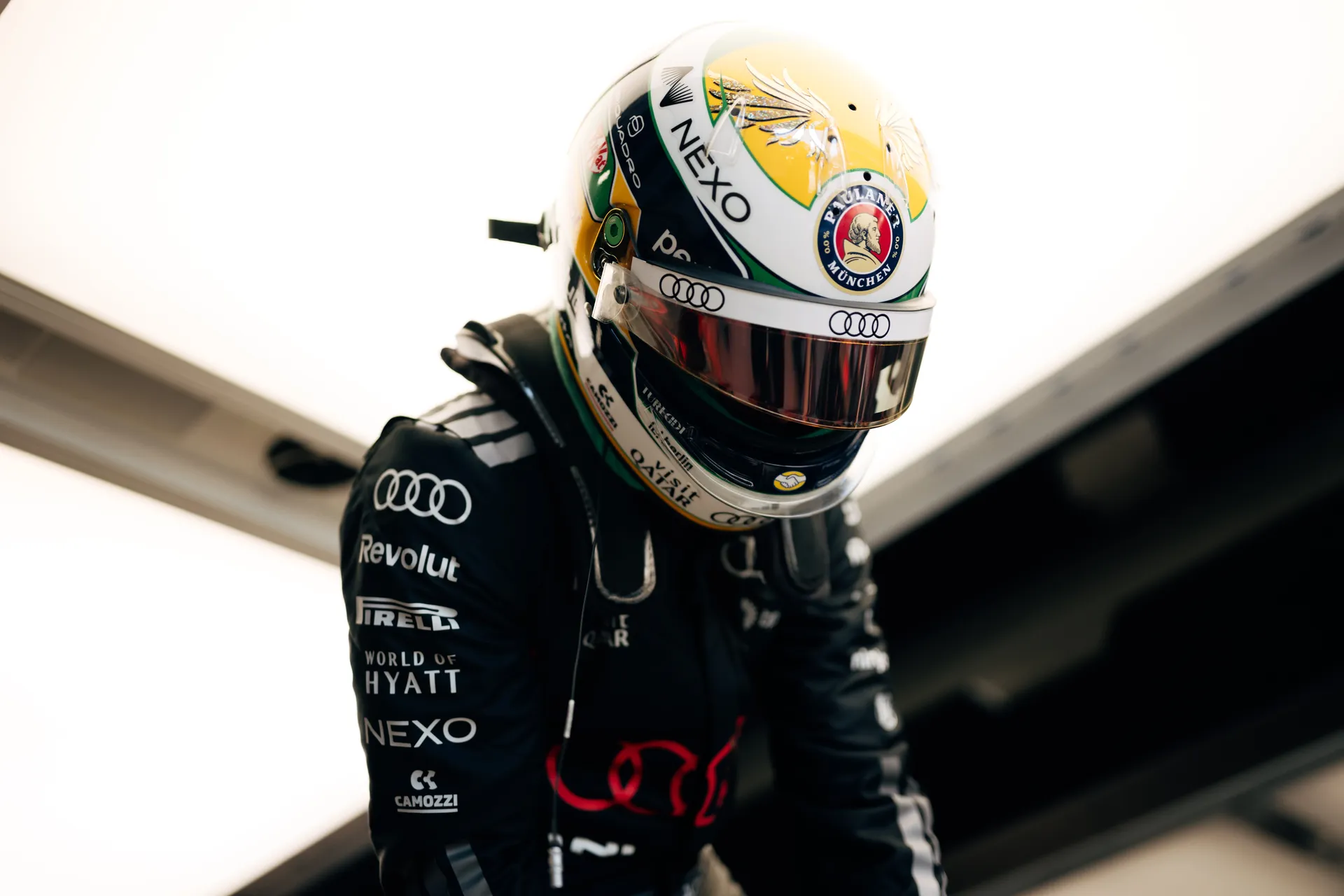 Gabriel Bortoleto wearing a green and yellow helmet with Brazilian flag details, preparing in the garage before heading out