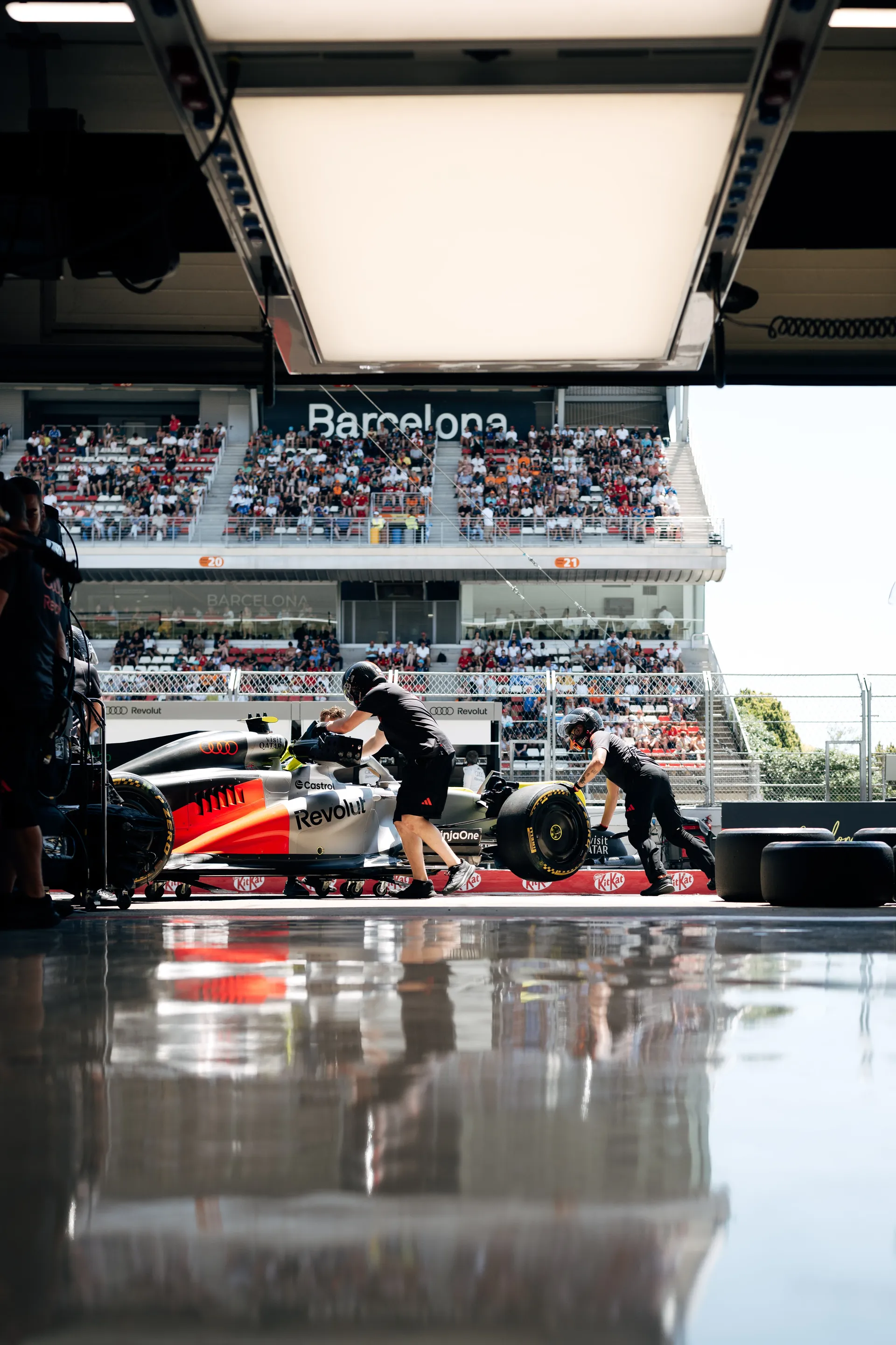 Audi Revolut F1® Team mechanics pushing the Formula One car out of the garage onto the pit lane at Circuit de Barcelona-Catalunya during qualifying preparations