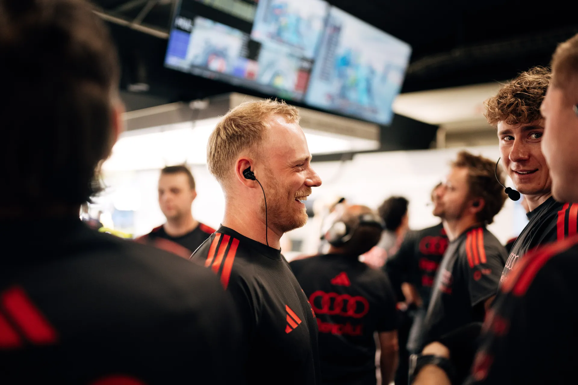 Audi Revolut F1® Team engineers gathered in the garage, smiling and interacting during a brief moment between qualifying runs
