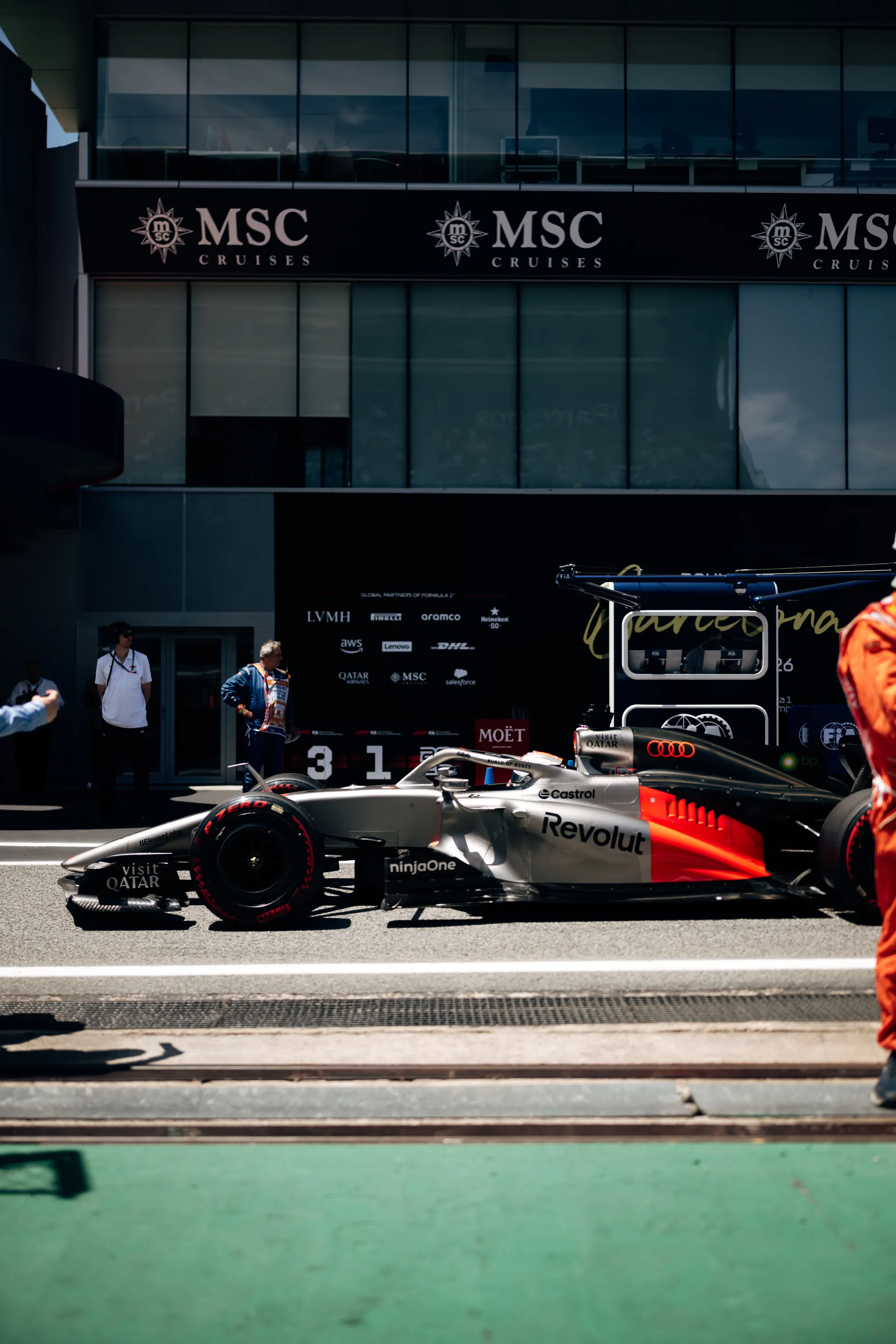 Audi R26 positioned on the Barcelona grid with Audi Revolut F1® Team mechanics preparing the car ahead of the race start.