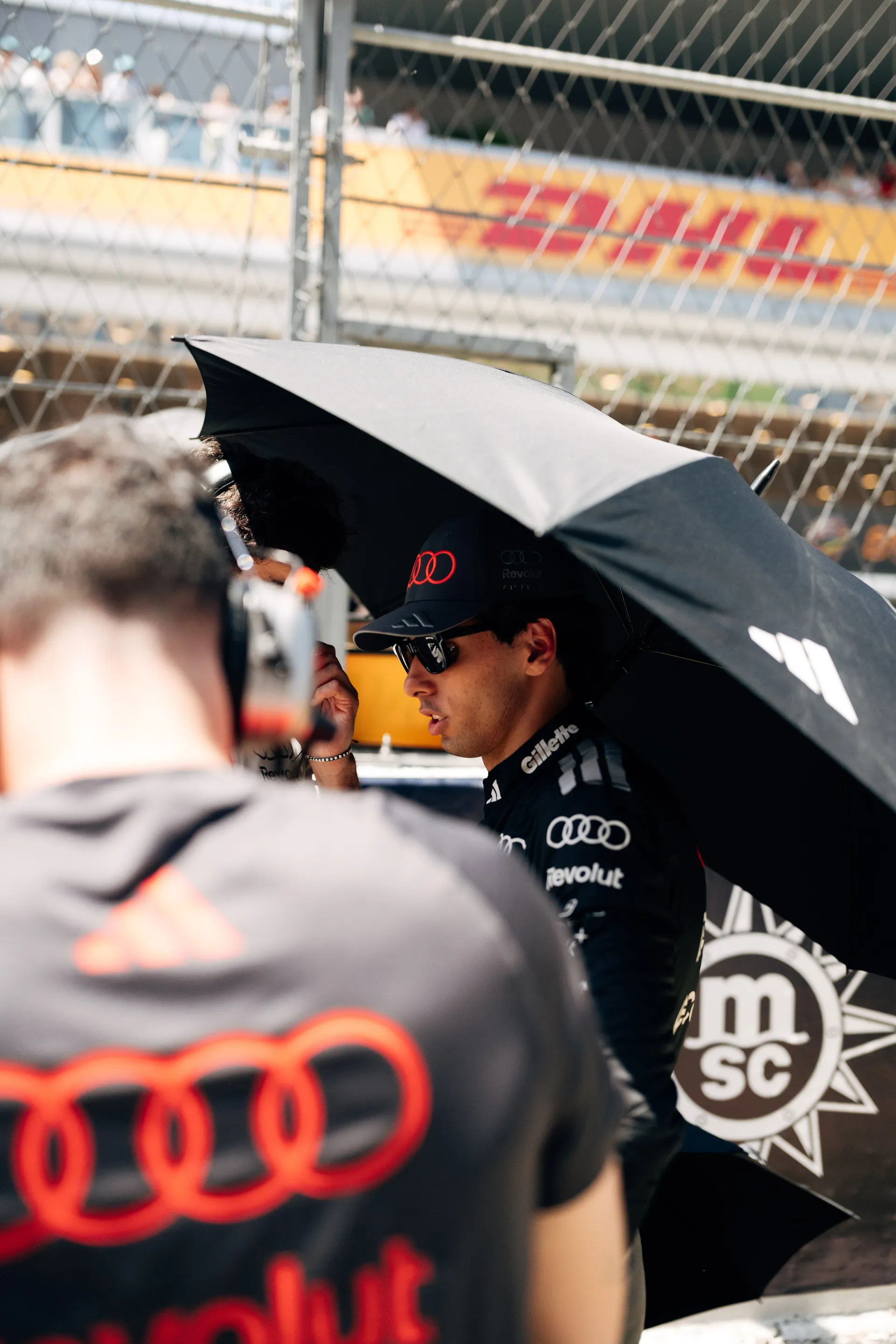 Gabriel Bortoleto standing under an umbrella on the Barcelona grid, preparing for the race with Audi Revolut F1® Team.