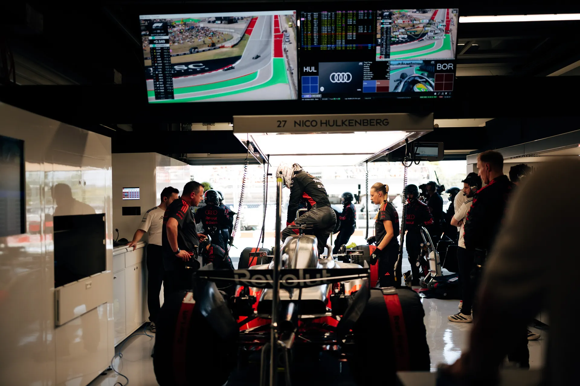 Nico Hulkenberg stepping into the Audi R26 in the garage while Audi Revolut F1® Team mechanics prepare the car.