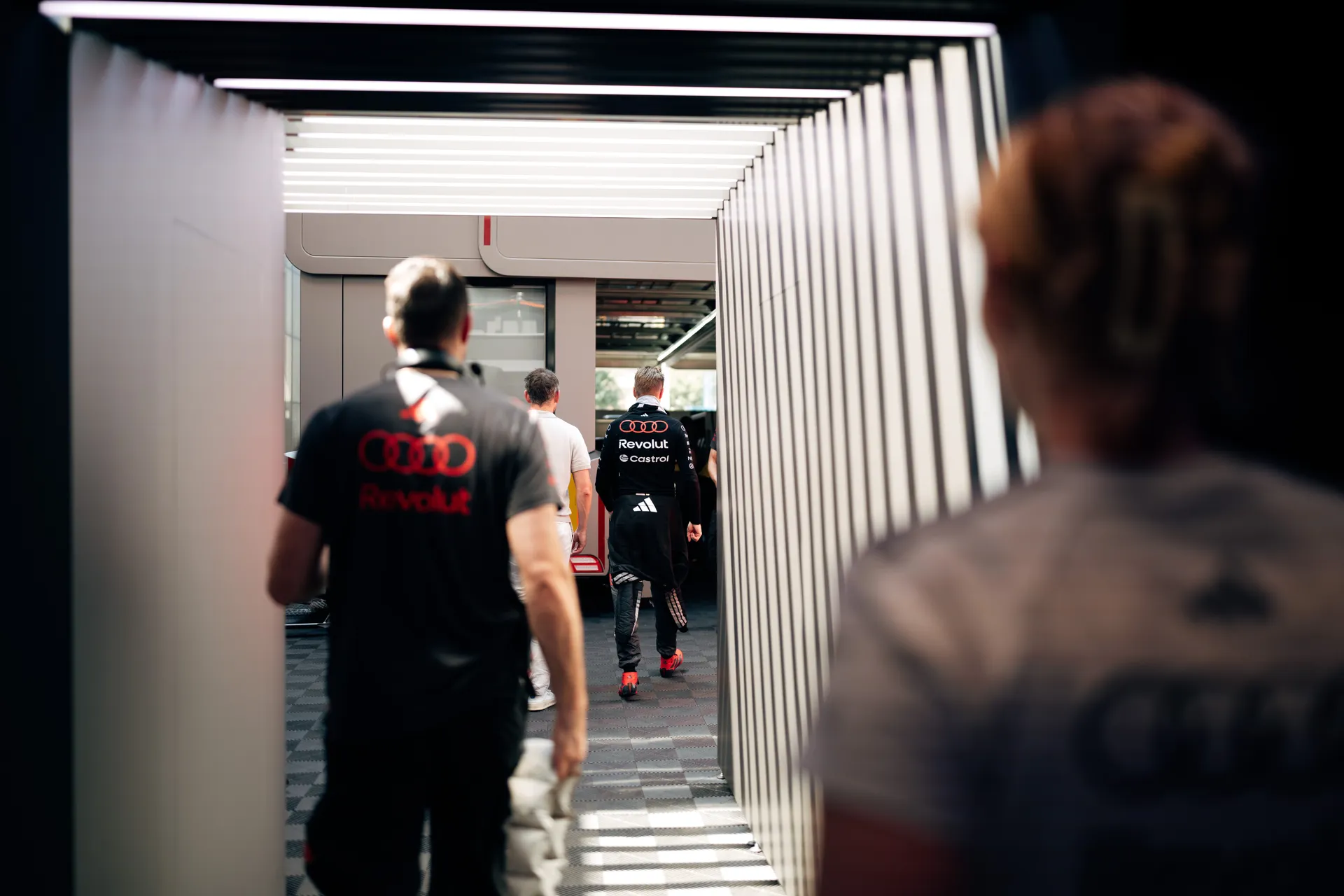 Audi Revolut F1® Team members and Nico Hulkenberg walking through the paddock corridor toward the garage during the Barcelona race weekend.
