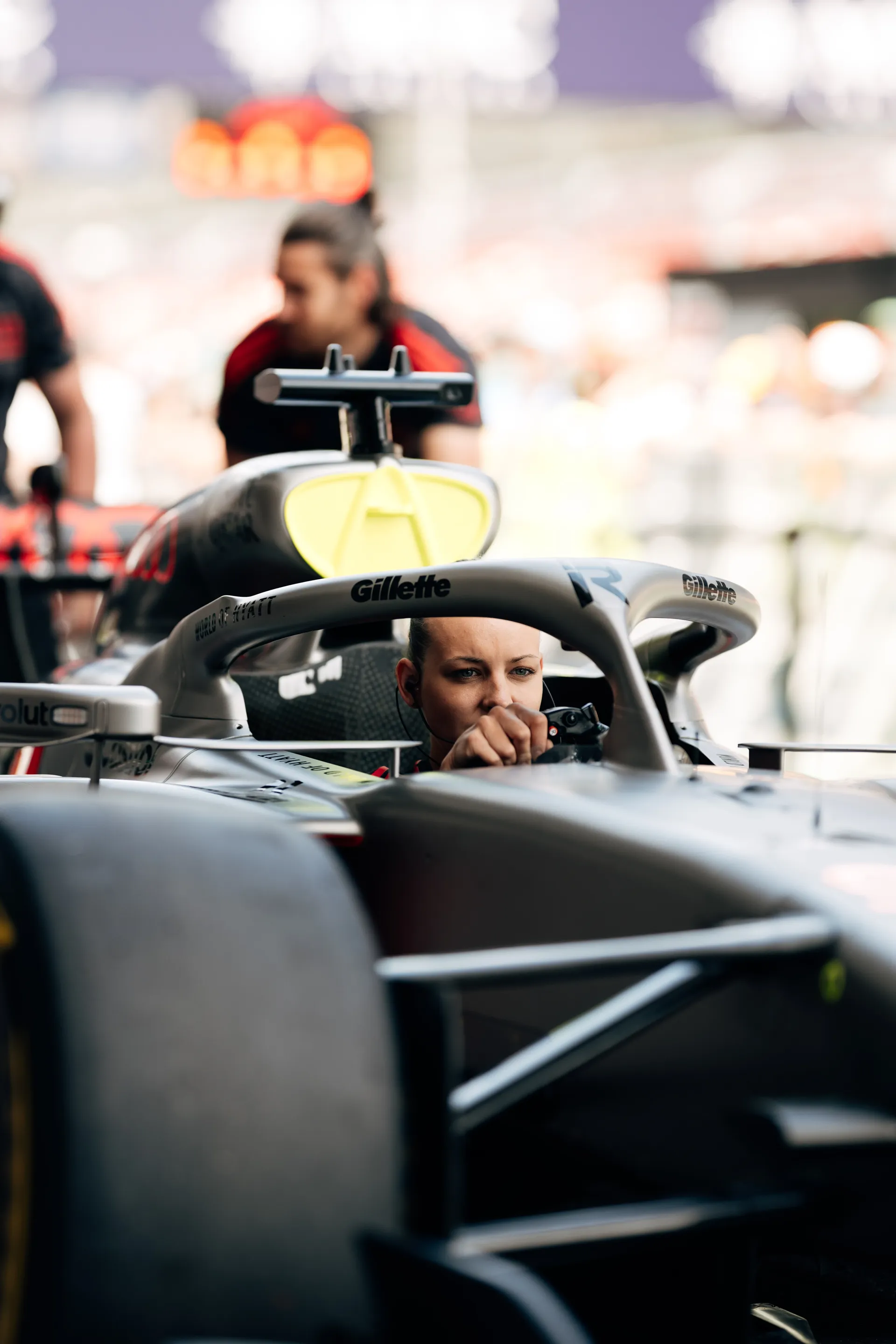 Audi Revolut F1® Team mechanic leans into the cockpit, adjusting controls and preparing the car before a session.