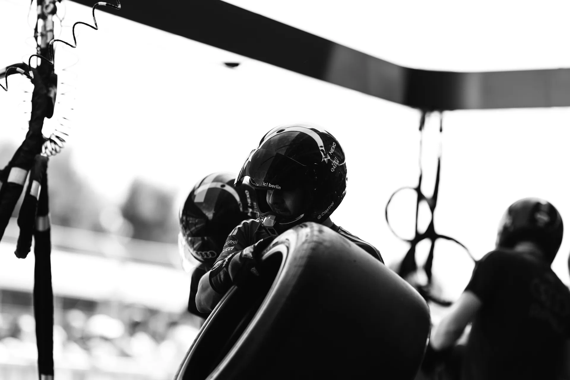 Black and white shot of a pit crew member holding a tire, preparing for a pit stop sequence.