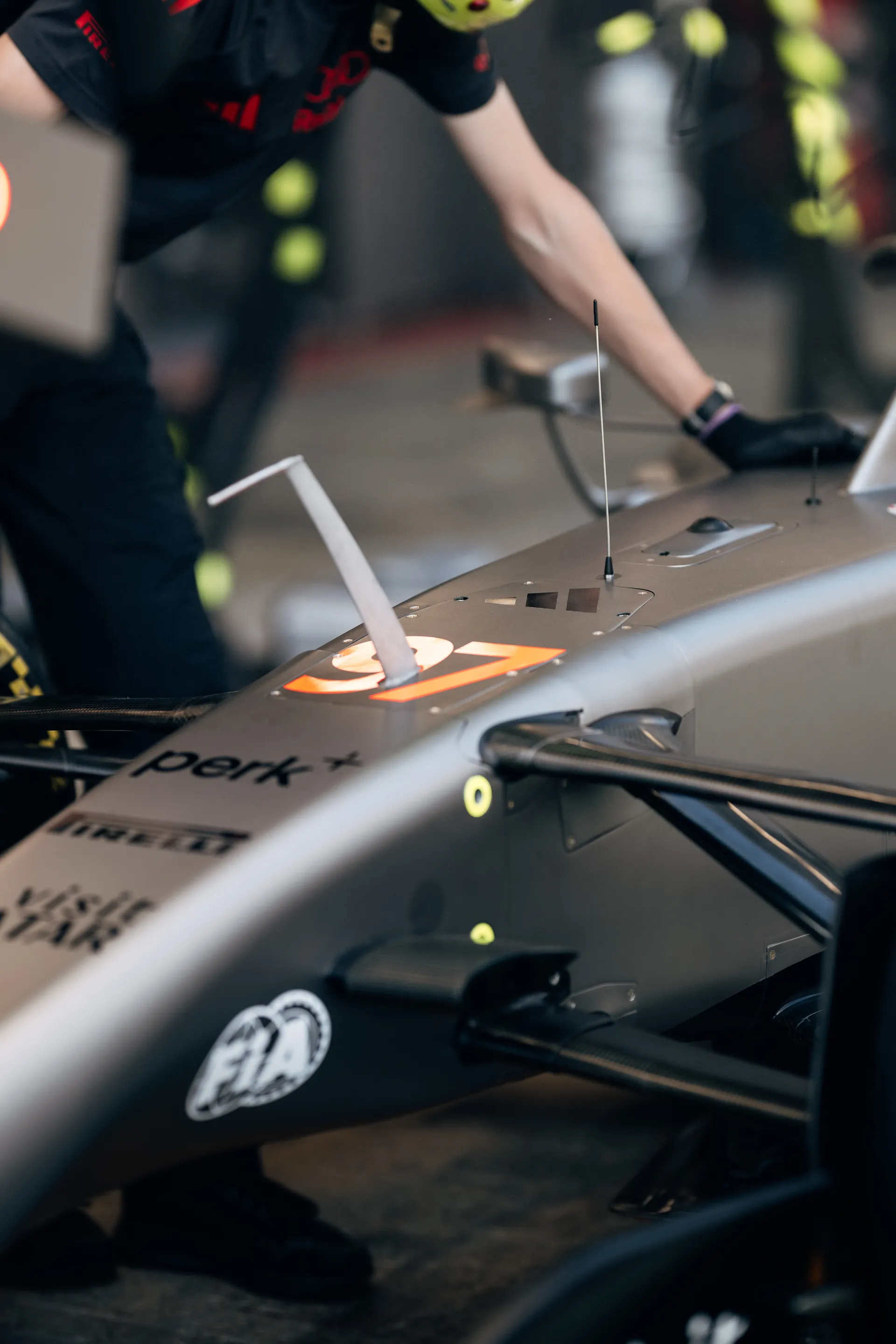 Close-up of the Audi Revolut F1® Team car body with antenna and number panel, as a mechanic reaches across the chassis.