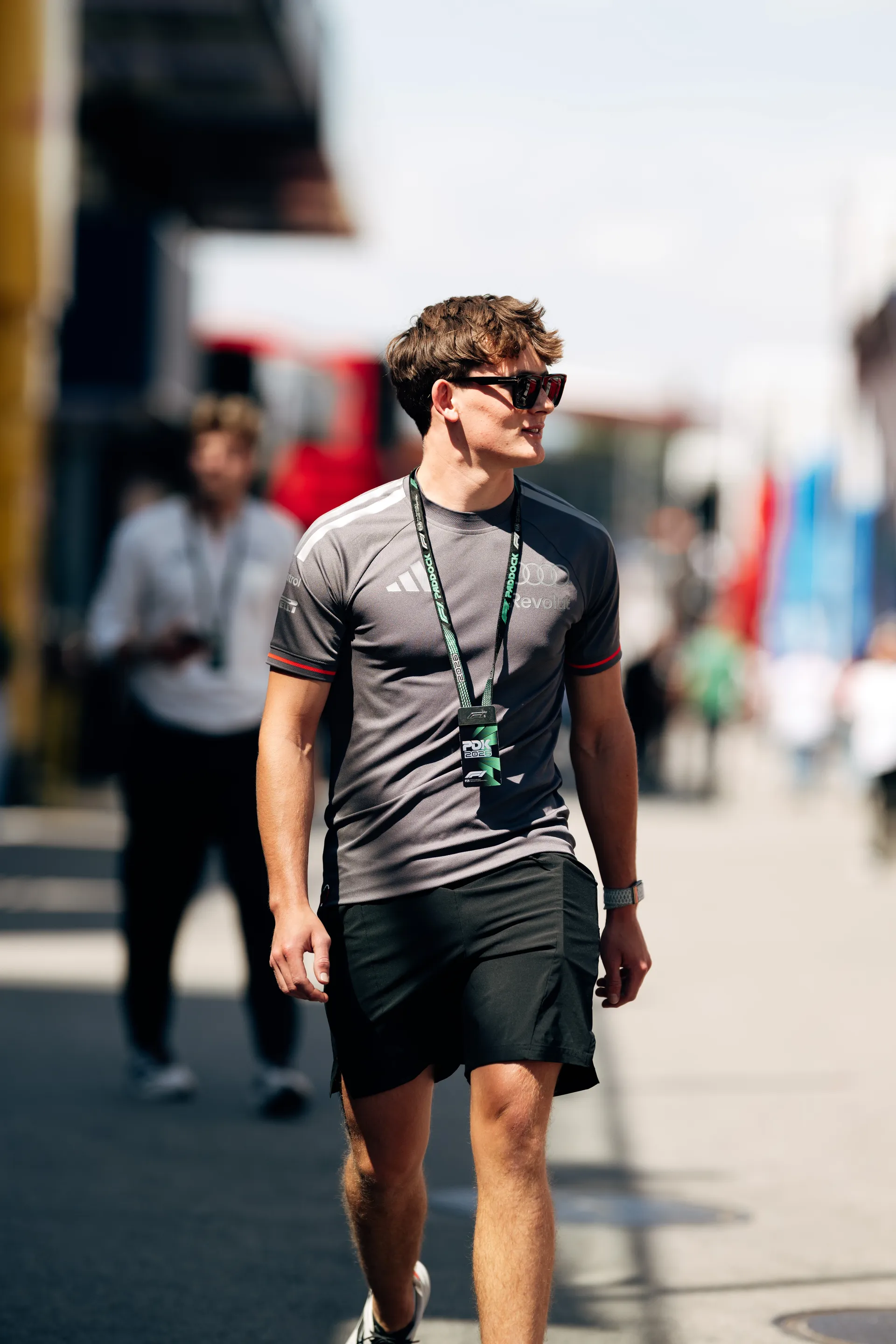 Paul Aron walking through the paddock wearing Audi Revolut F1® Team kit and accreditation pass.