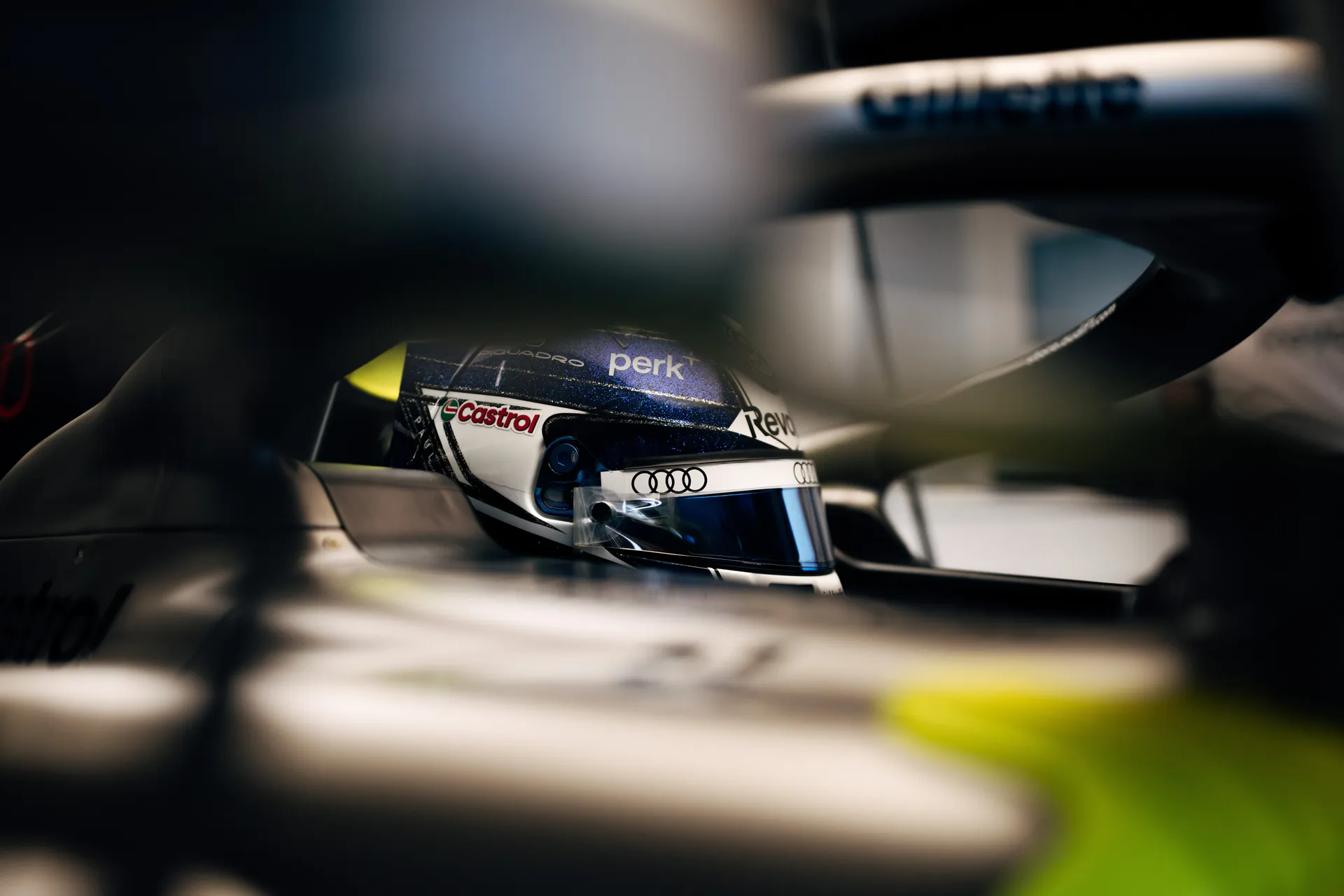 Close-up of Paul Aron inside the cockpit wearing a blue helmet, focused before or during a session.