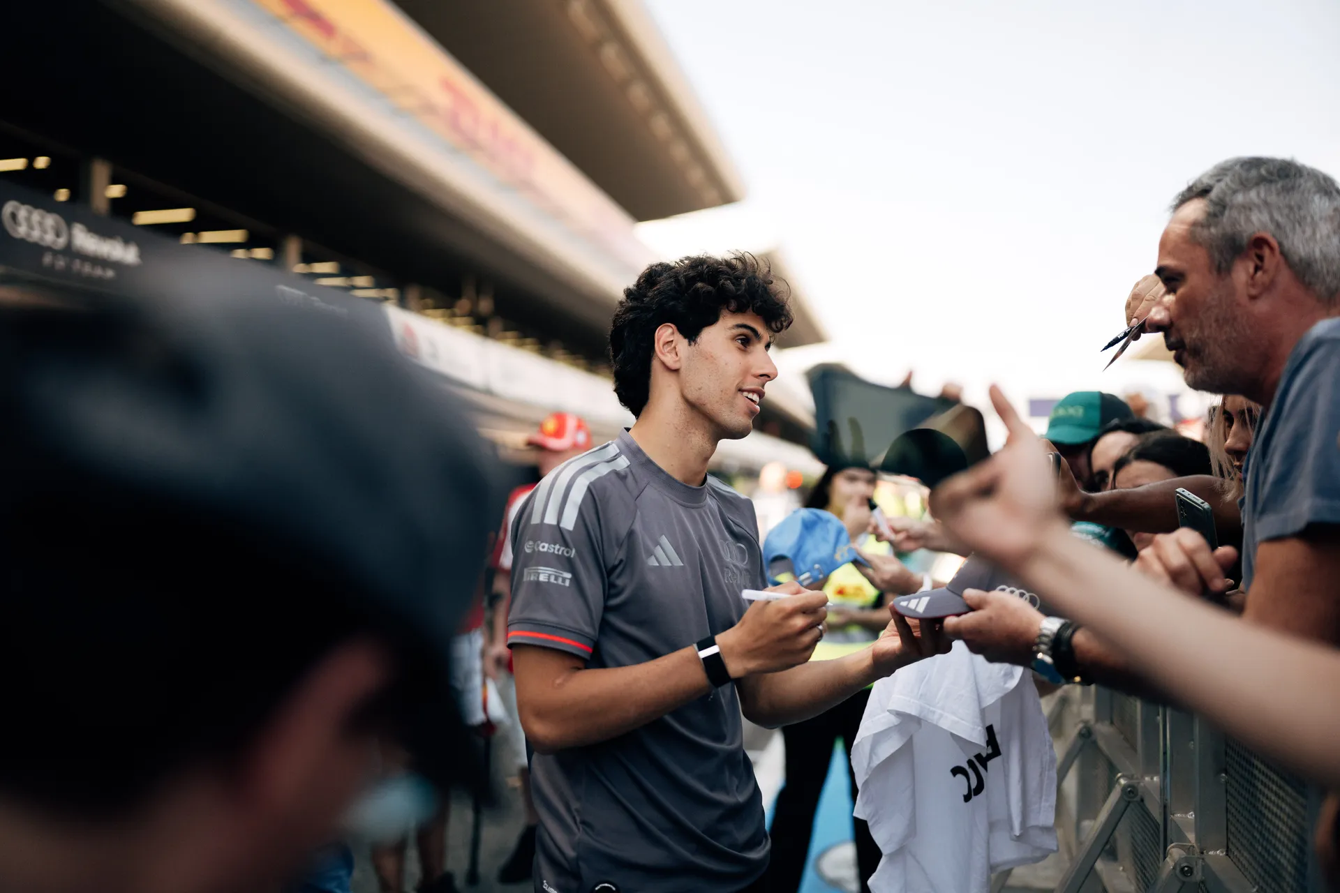 Gabriel Bortoleto signs autographs for fans along the paddock barrier, interacting closely with the crowd during a race weekend.