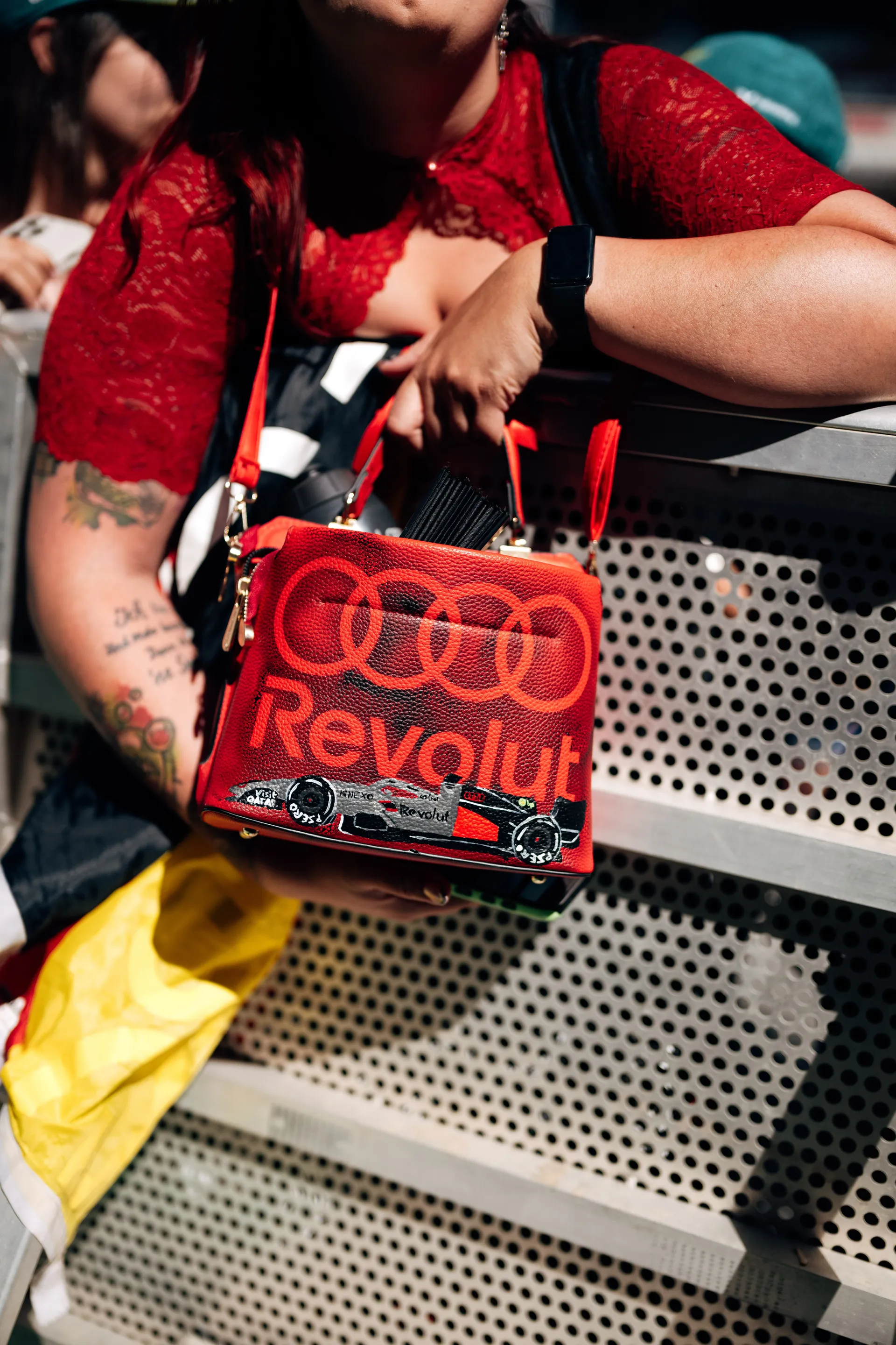 Fan holding a red custom handbag featuring Audi Revolut F1® Team branding and a hand-painted Formula One car design.
