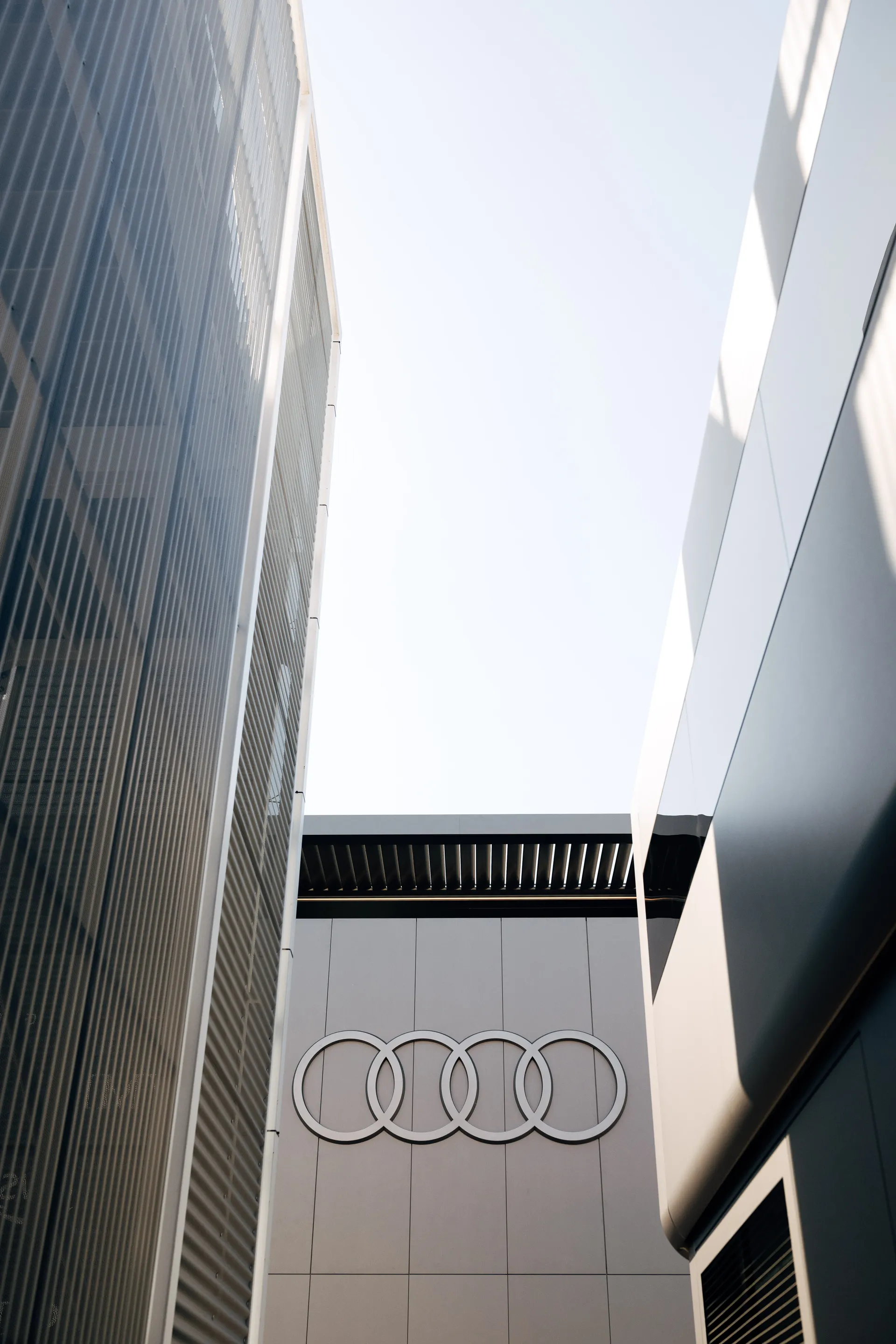 Architectural view of Audi branding on a paddock building, with the four rings logo centered between modern structures.