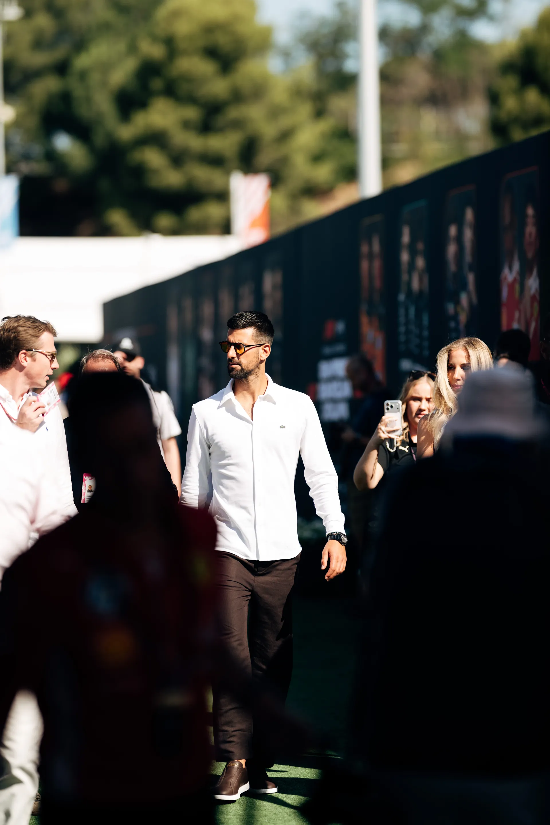 Novak Djokovic walking through the paddock, surrounded by fans and team members during the Barcelona race weekend