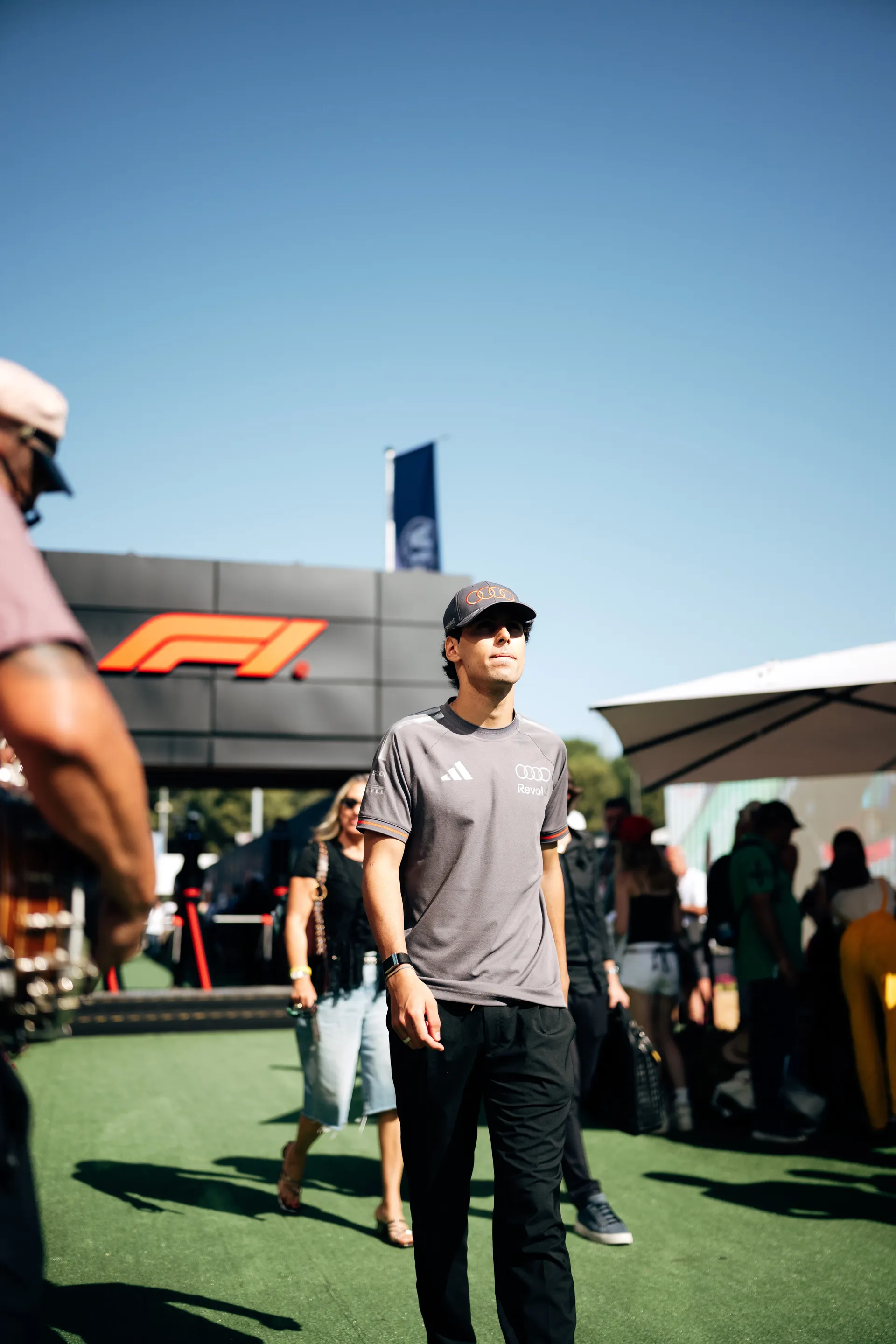 Gabriel Bortoleto walking past the Formula 1 paddock entrance with team branding in the background