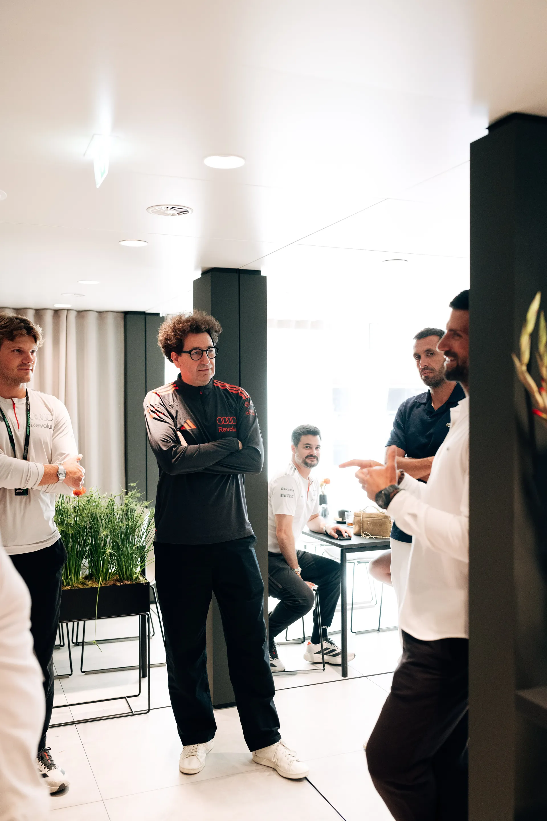 Novak Djokovic speaking with Mattia Binotto andteam personnel inside the Audi Revolut F1® Team hospitality area