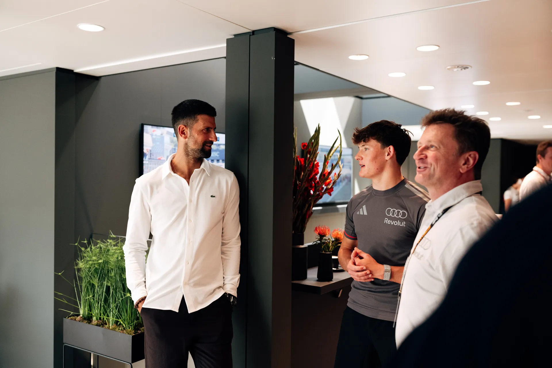 Gabriel Bortoleto interacting with Freddie Slater and multiple Formula 1 drivers in a group setting inside the paddock