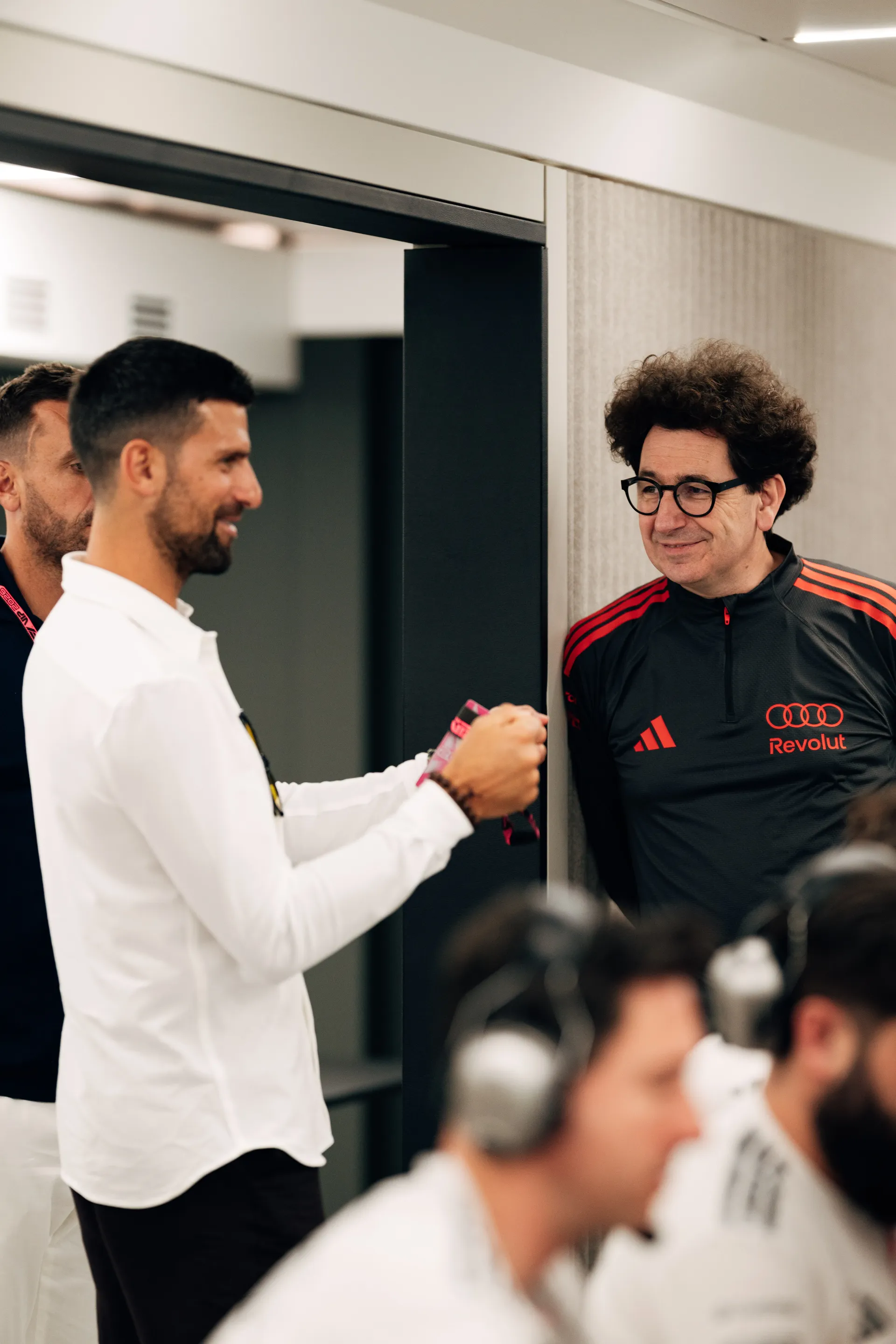 Novak Djokovic speaking with Mattia Binotto and team personnel inside the Audi Revolut F1® Team hospitality area