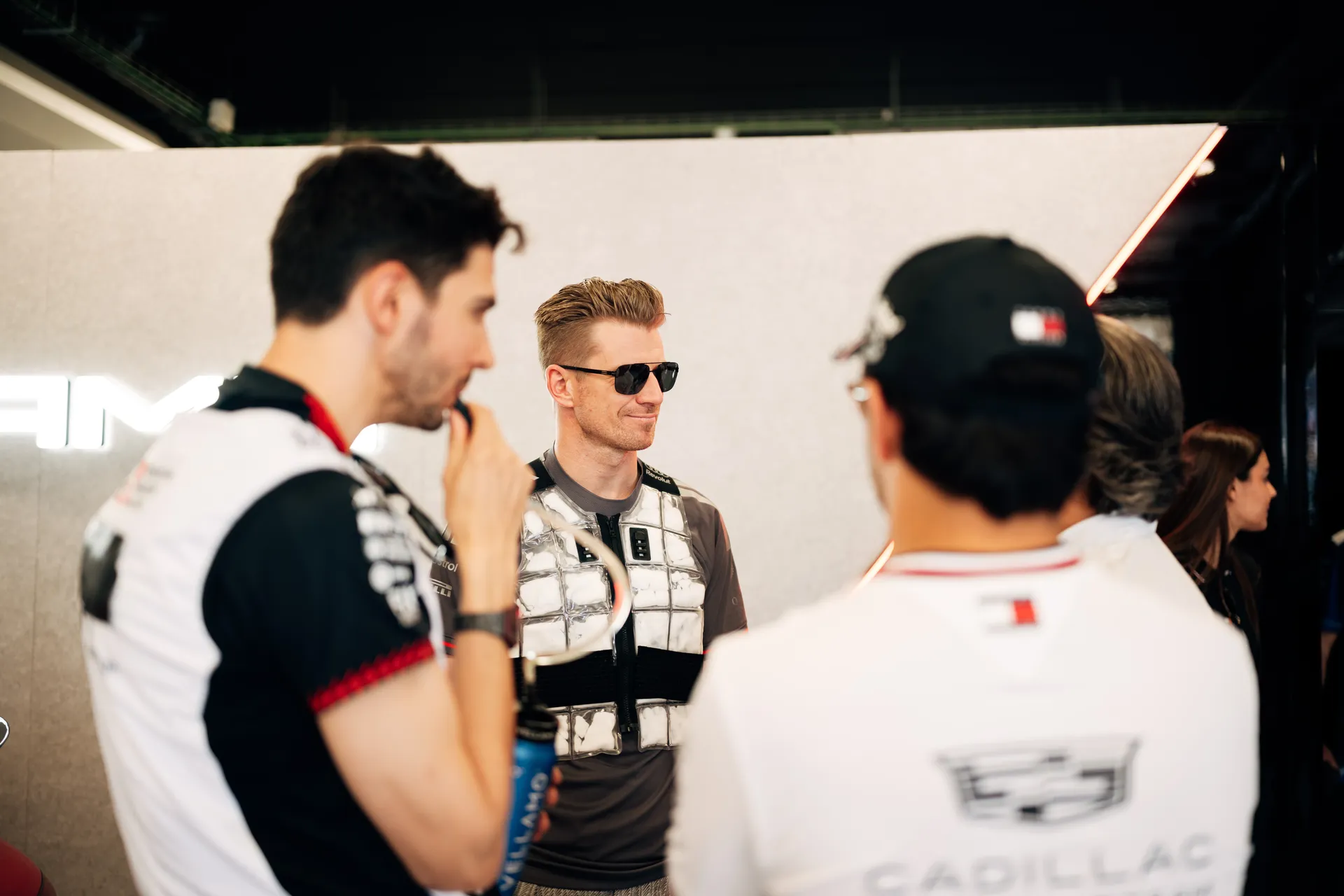 Nico Hulkenberg standing with drivers in the Audi Revolut F1® Team garage during a paddock conversation