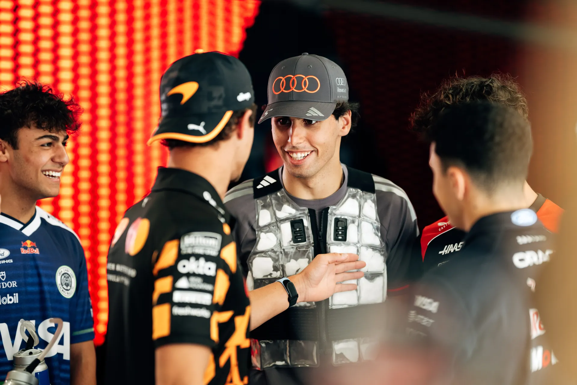 Gabriel Bortoleto smiling and engaging in conversation with fellow drivers in a relaxed behind the scenes paddock moment