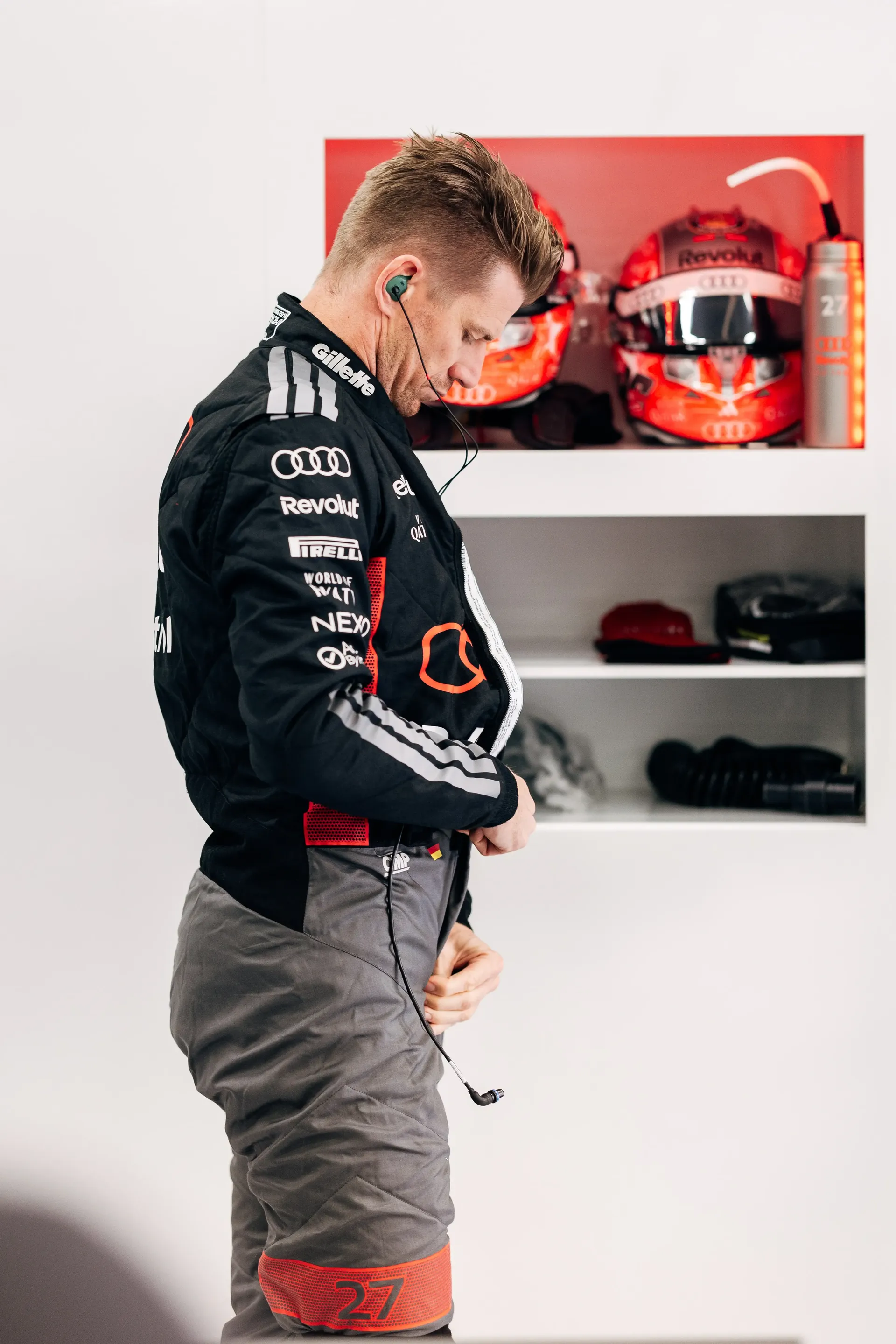 Nico Hulkenberg adjusts his race suit inside the Audi Revolut F1® Team garage during pre-session preparations.