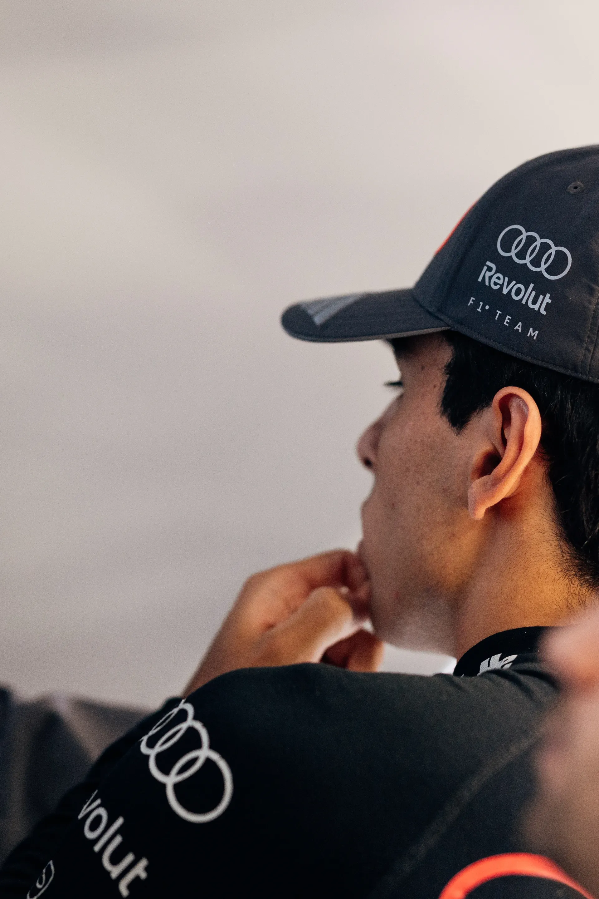 Gabriel Bortoleto stands inside the Audi Revolut F1® Team garage wearing team kit, focused ahead before the session.