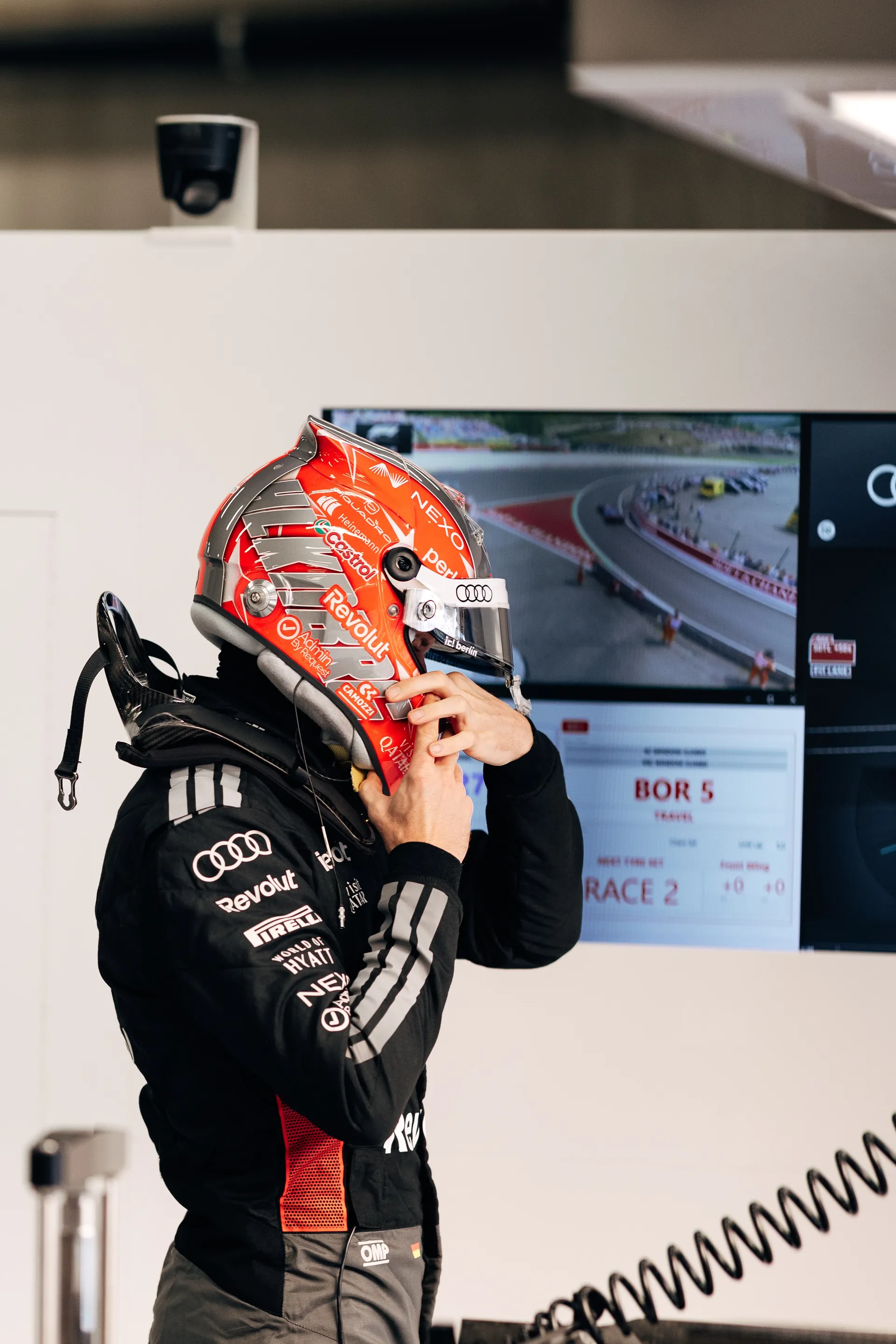 Nico Hulkenberg prepares in the Audi Revolut F1® Team garage while reviewing track footage on a monitor.