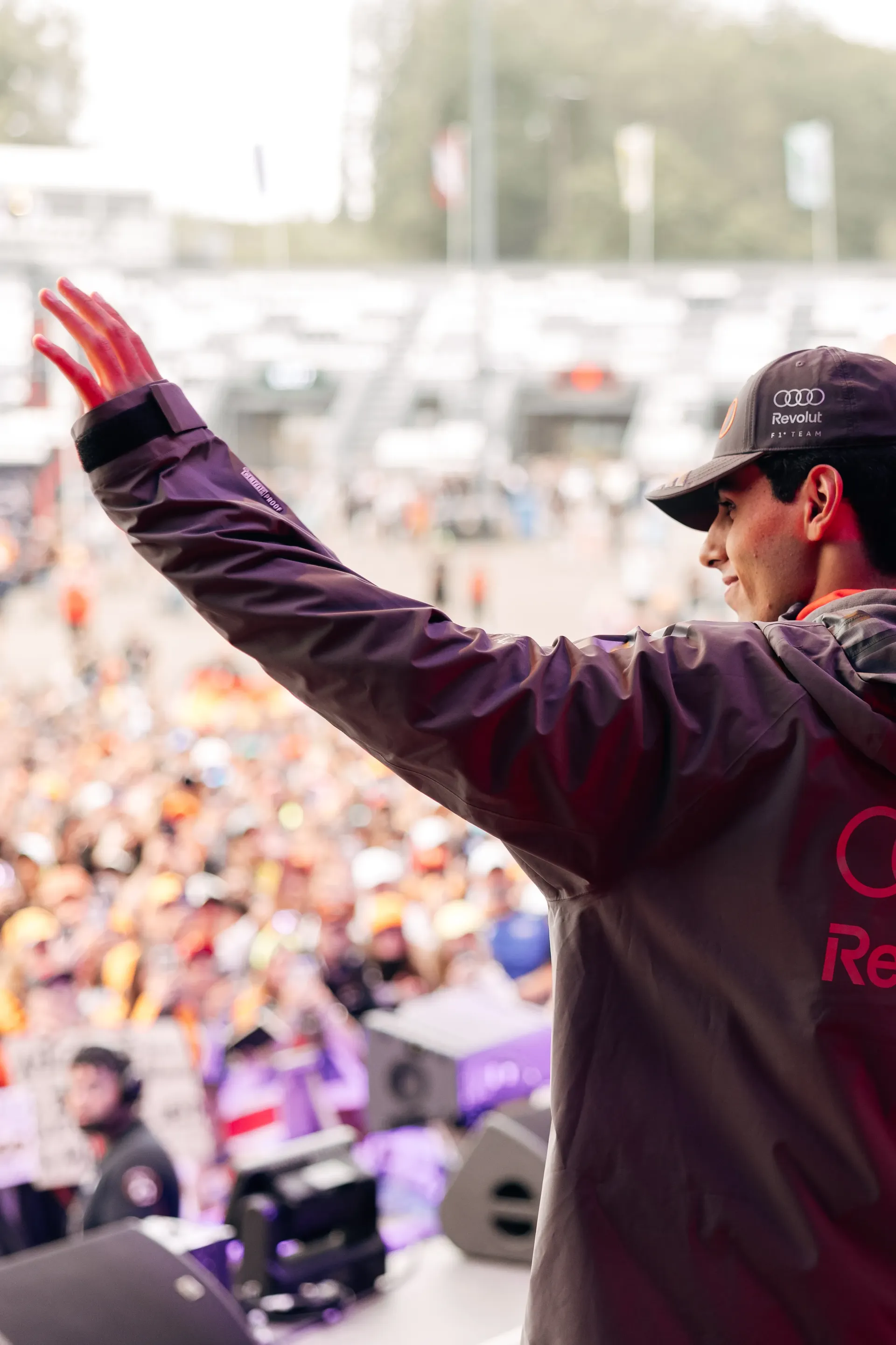 Gabriel Bortoleto waves to a large crowd during the Belgian Grand Prix fan forum, standing on stage in Audi Revolut F1® Team apparel.
