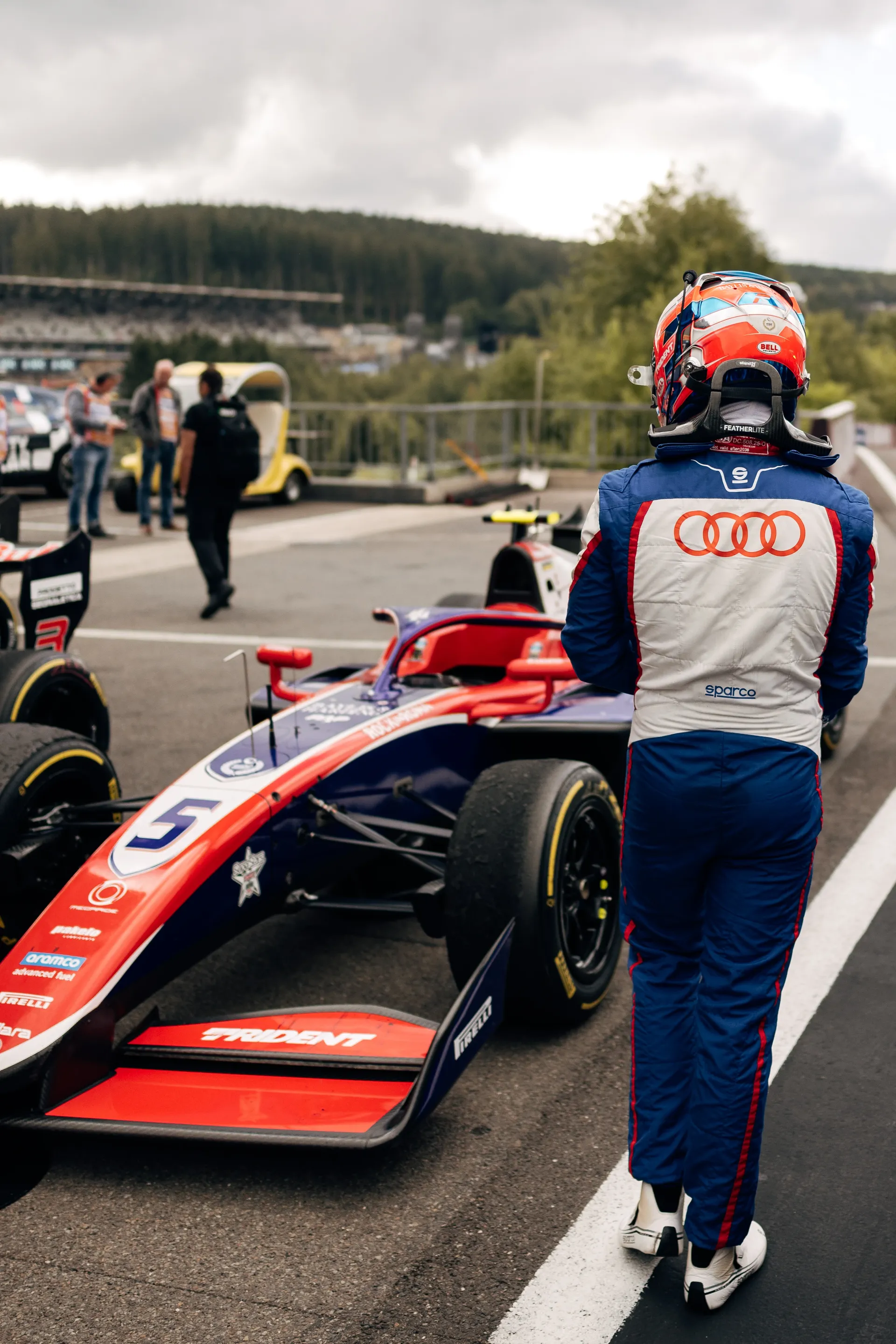 Freddie Slater walks along the Spa Francorchamps paddock past his Formula 3 car after securing a podium finish