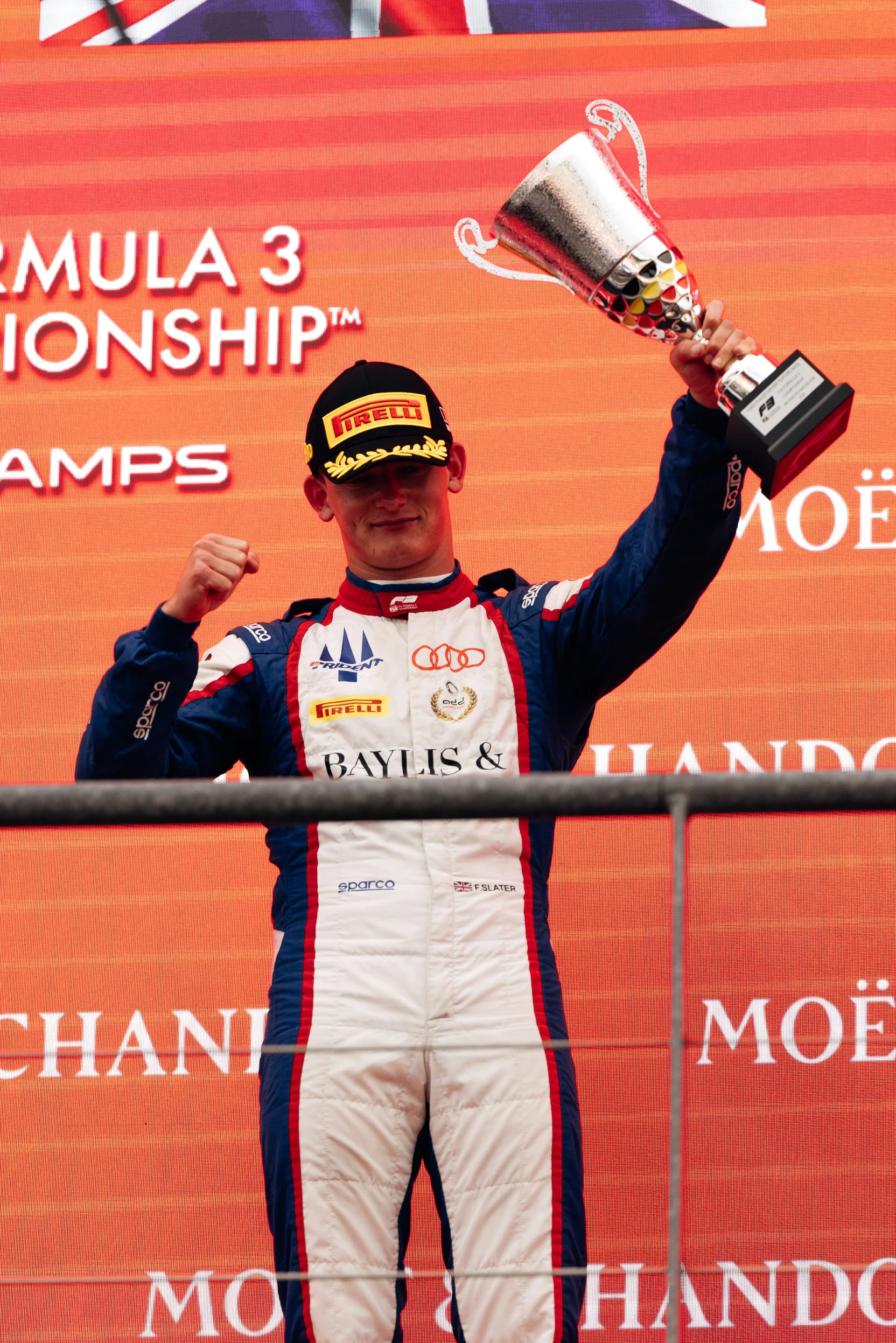 Freddie Slater celebrates on the podium holding his trophy after finishing P3 at the Belgian Grand Prix Formula 3 race