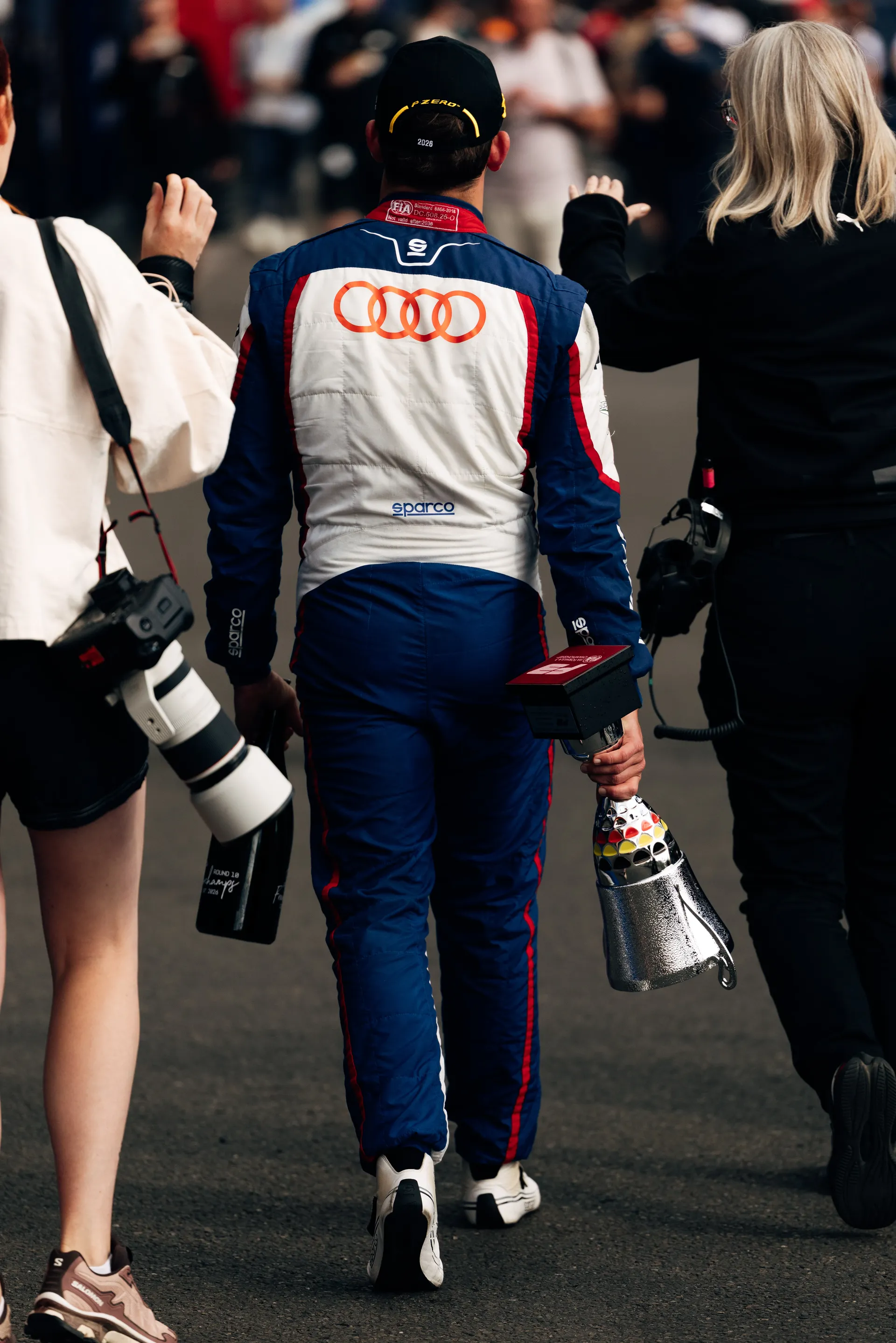 Freddie Slater walks away from the podium carrying his trophy through the paddock at Spa Francorchamps after his P3 finish