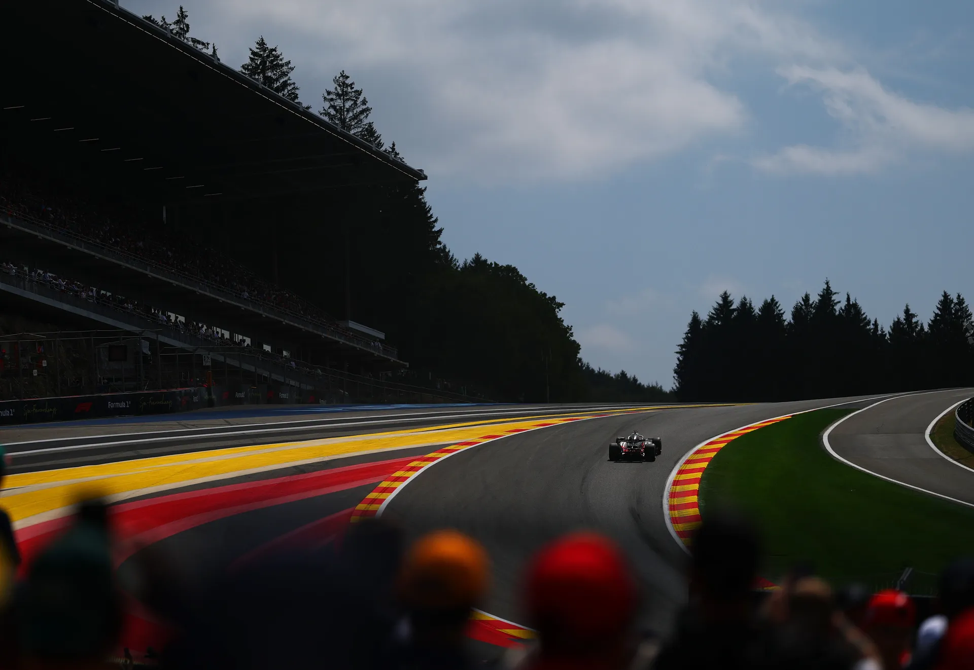 Long shot of Audi R26 of Audi Revolut F1® Team driving uphill through the Spa forest landscape